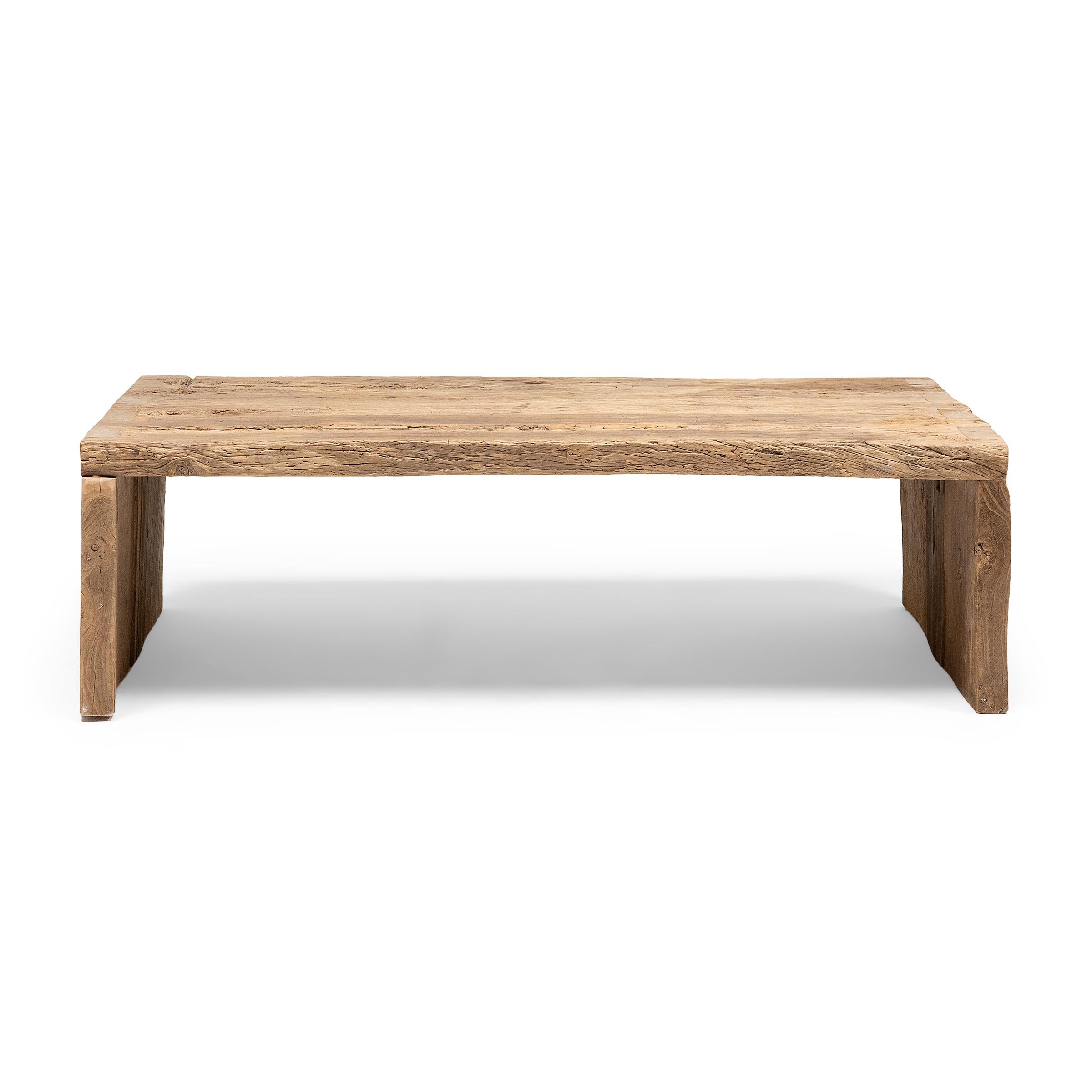 Cette table basse artisanale est une célébration du style wabi-sabi. Fabriquée en bois d'orme épais récupéré de l'architecture de la dynastie Qing, la table présente un design minimaliste en cascade et est laissée brute pour préserver la beauté