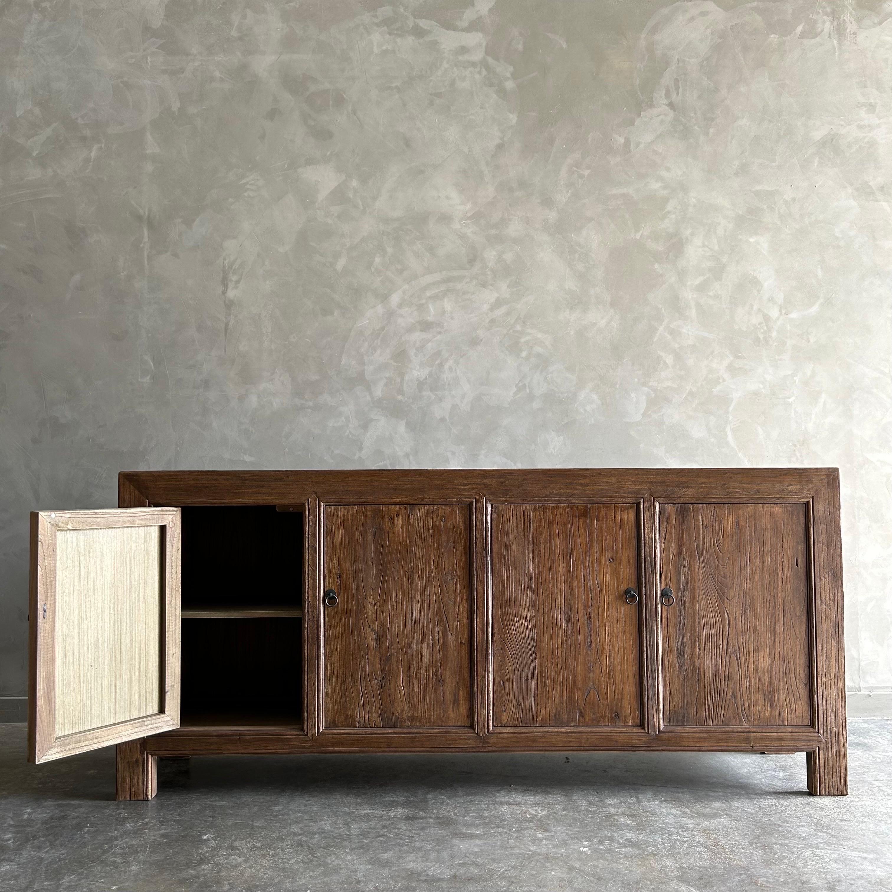 Armario de 4 puertas de madera de olmo recuperada. 
Estas viejas maderas de olmo se muestran en su forma más primigenia y natural. Los métodos de construcción artesanales resaltan el bello veteado de la madera de olmo y los nudos y fisuras de su