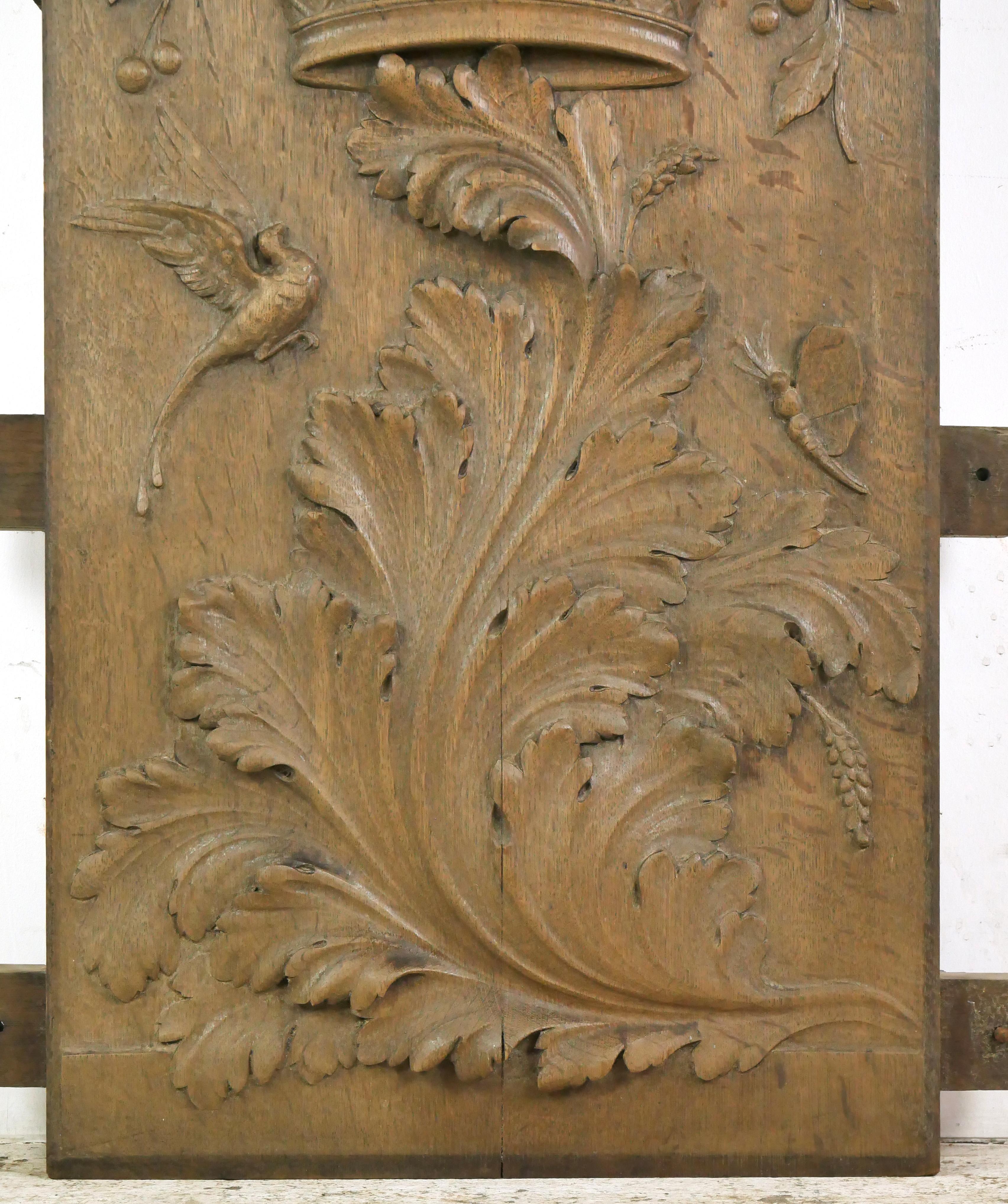 Reclaimed European fireplace panel made of wood with a dark wood tone. The carvings feature a figural face, floral filled basket, and a large acanthus leaf. Good condition with a split in wood and surface wear and tear. One available. Please note,