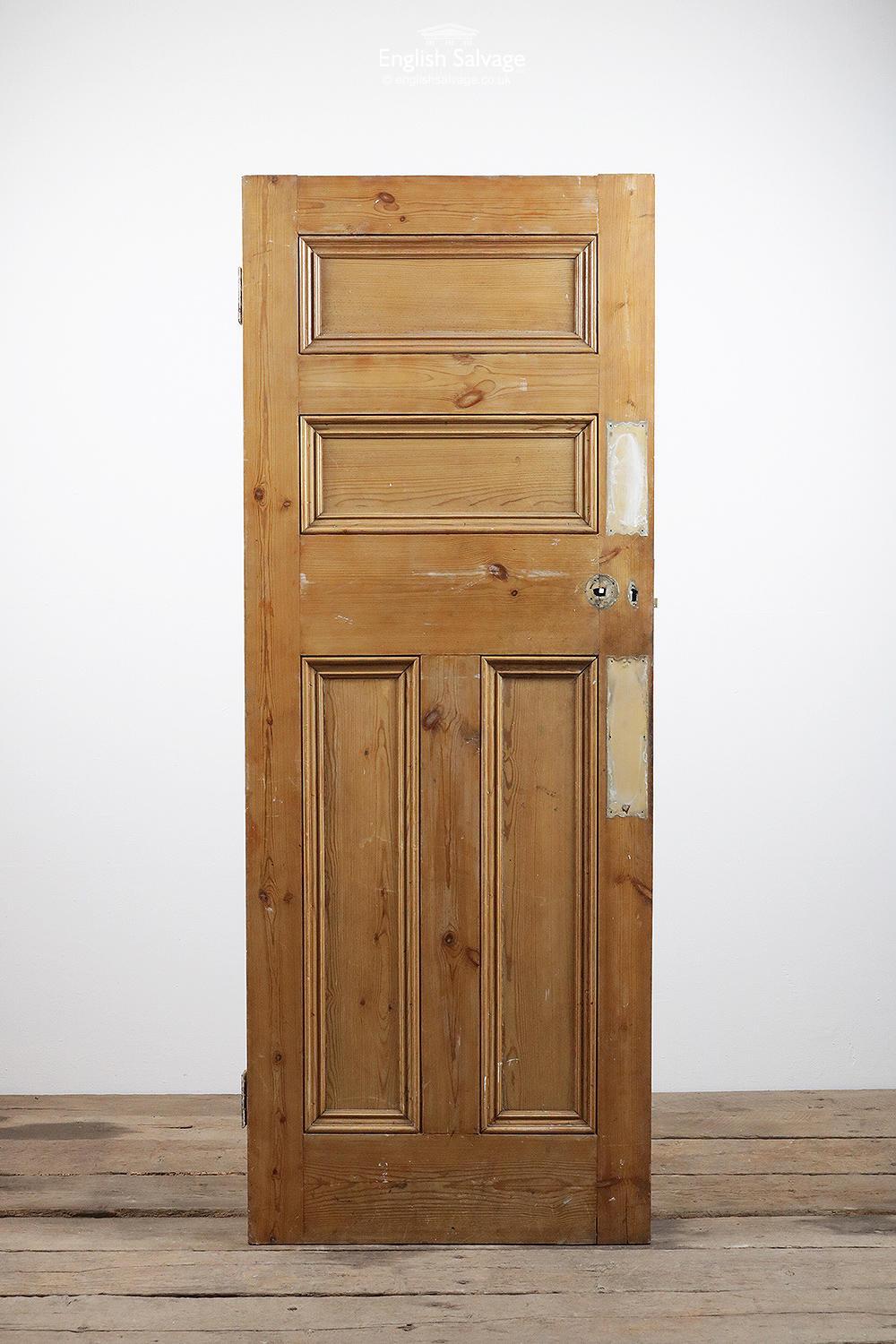 Reclaimed pine door with four beaded panels and two large hinges. Old push plate marks, an uneven top, plus lock, handle and nail holes.