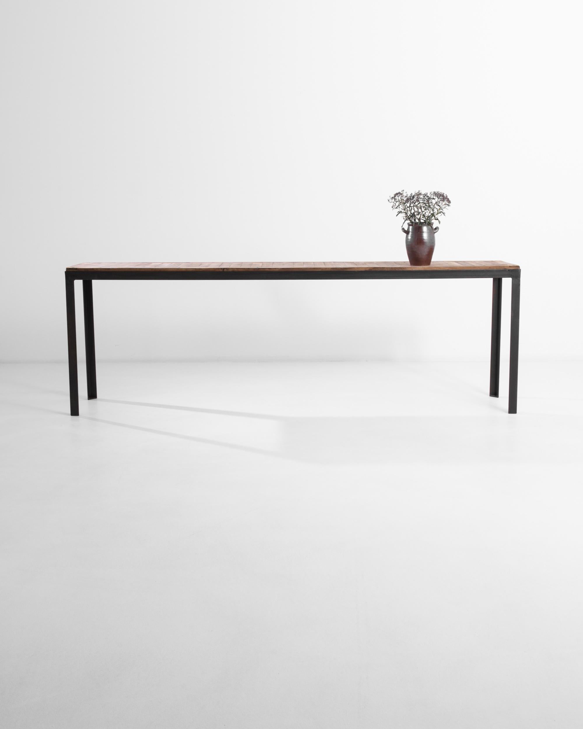 A console table from France, this piece features an elongated frame topped by elegant wooden panels, creating a sleek profile. The black metal creates a minimal frame for the reclaimed boards, completed by the beautifully patinated wood and its