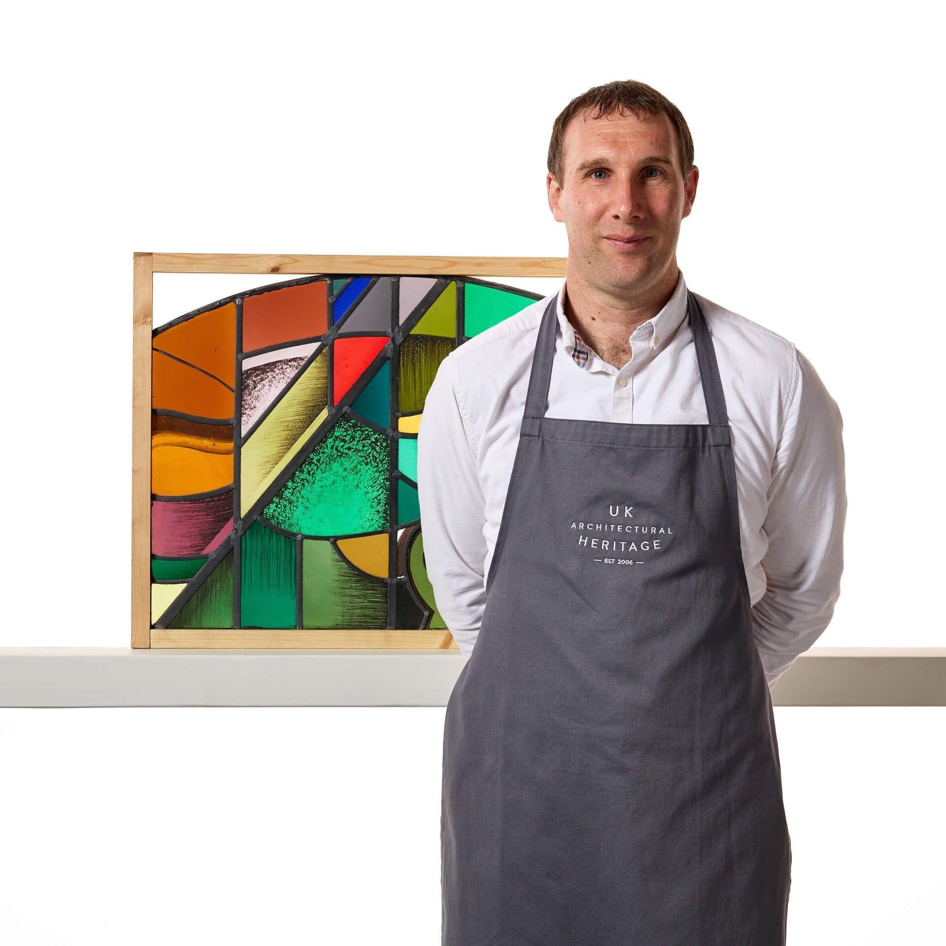 Vidriera en arco poco profundo de estilo abstracto, obra de Goddard y Gibbs, con una voluta pintada y una hoja estilizada.

Se trata de un panel abstracto de vidriera modernista con un diseño inusual, que combina una gama de colores vibrantes,
