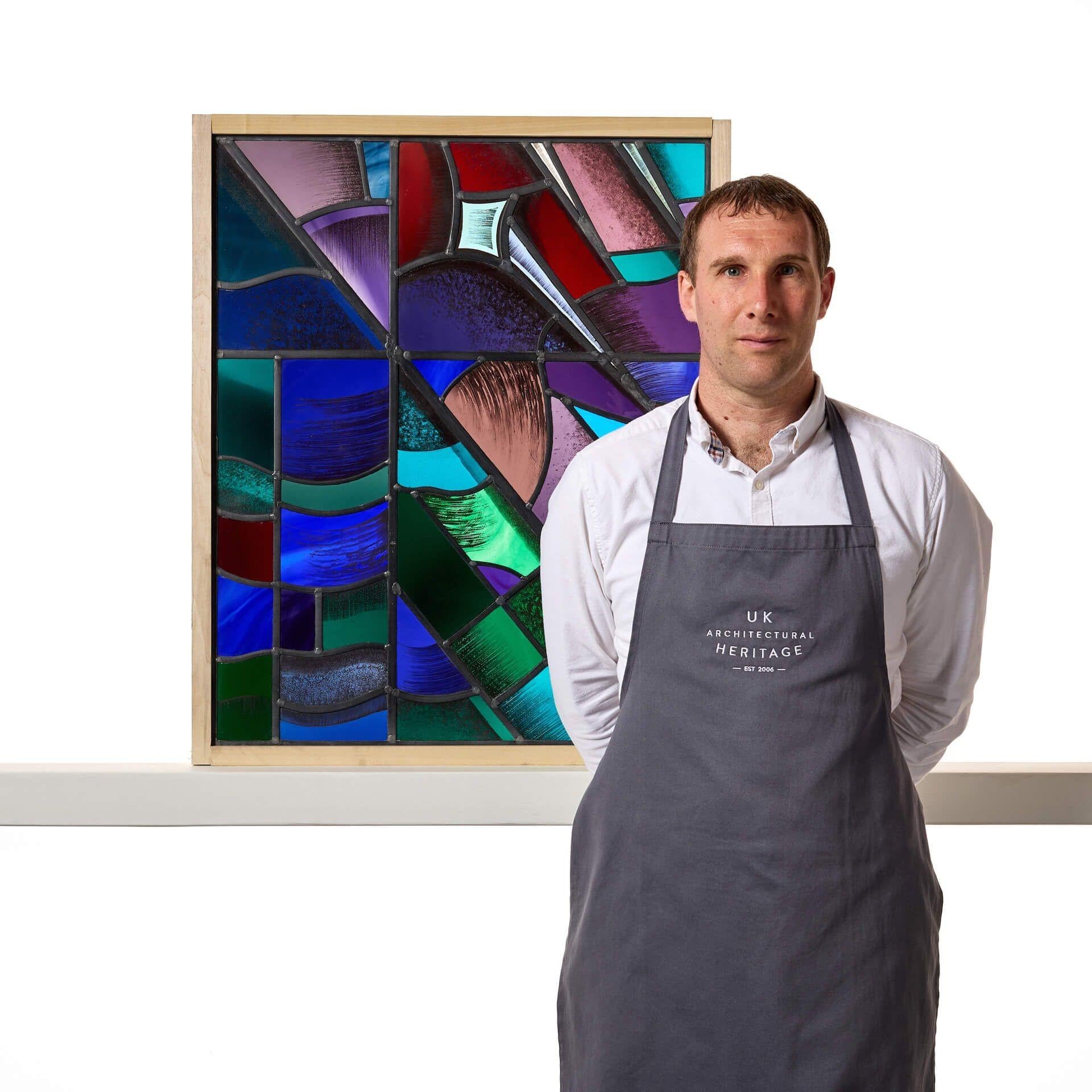 A stunning geometric, modernist style stained glass panel by renowned stained glass makers Goddard and Gibbs.

This is an abstract stained glass window in an unusual modern style, blending together a range of vivid and bright colours, such as