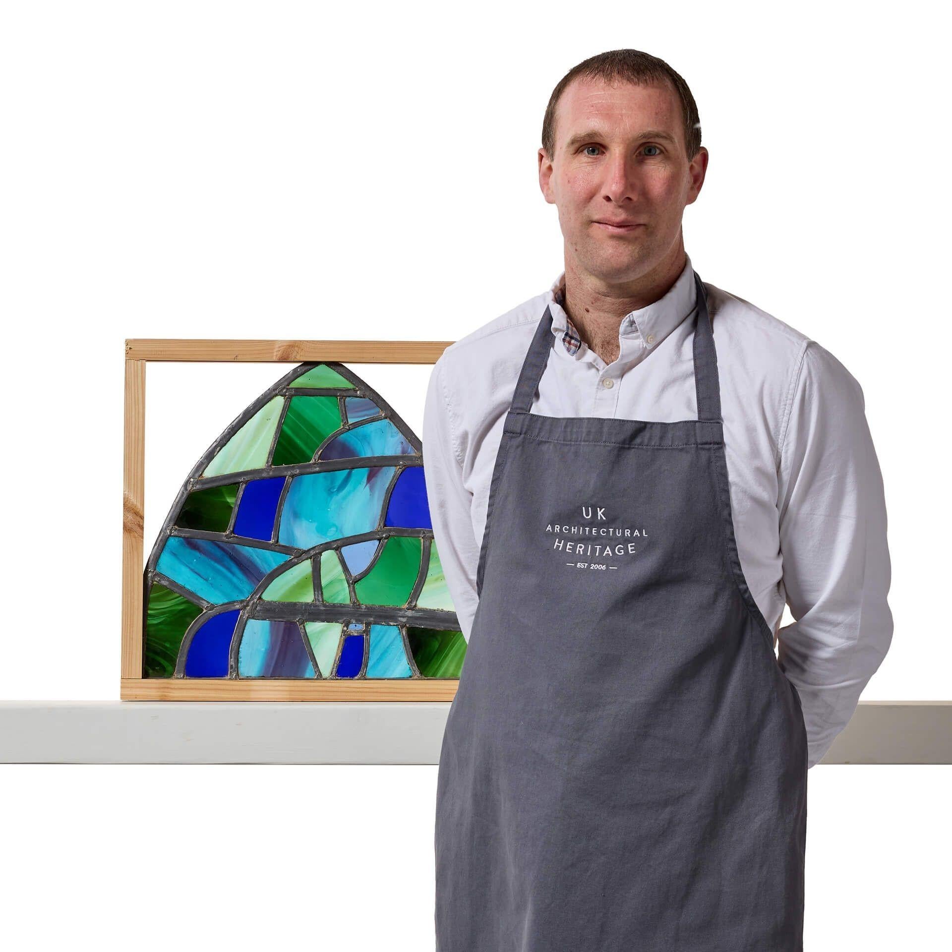 Un panneau de vitrail récupéré, arqué et coloré, composé de verre dans une variété de nuances de vert et de bleu. Ce vitrail provient des ateliers de Finnigan and Shaw, entreprise familiale de troisième génération de l'artiste Sax Shaw.
 
Ce petit