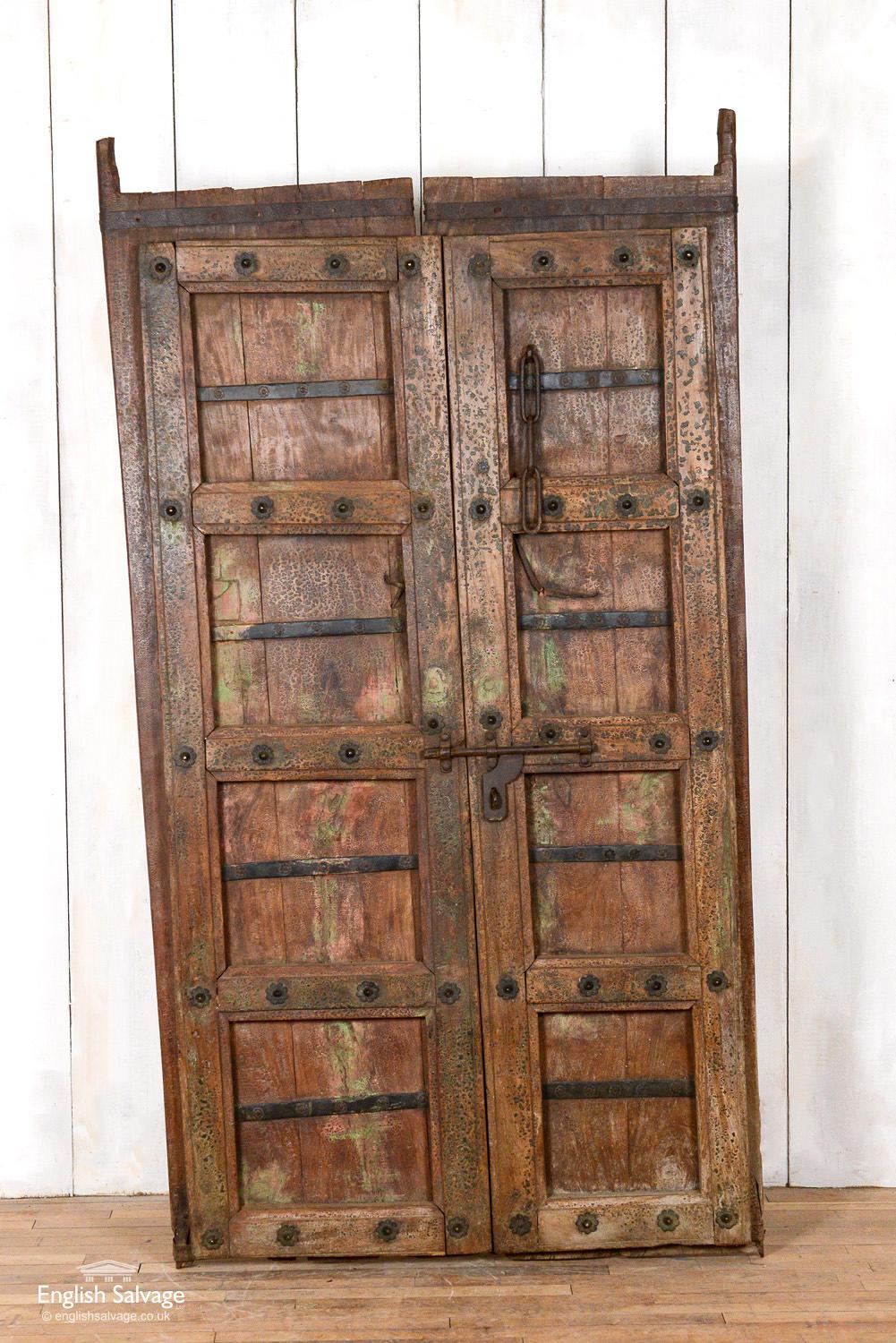 Old Indian teak panel made from a pair of doors. Barring at the back of the doors can be removed to make a pair of doors. Iron work studs and fixings give this door wonderful character. Some splits, scrapes and scuffs commensurate with age but