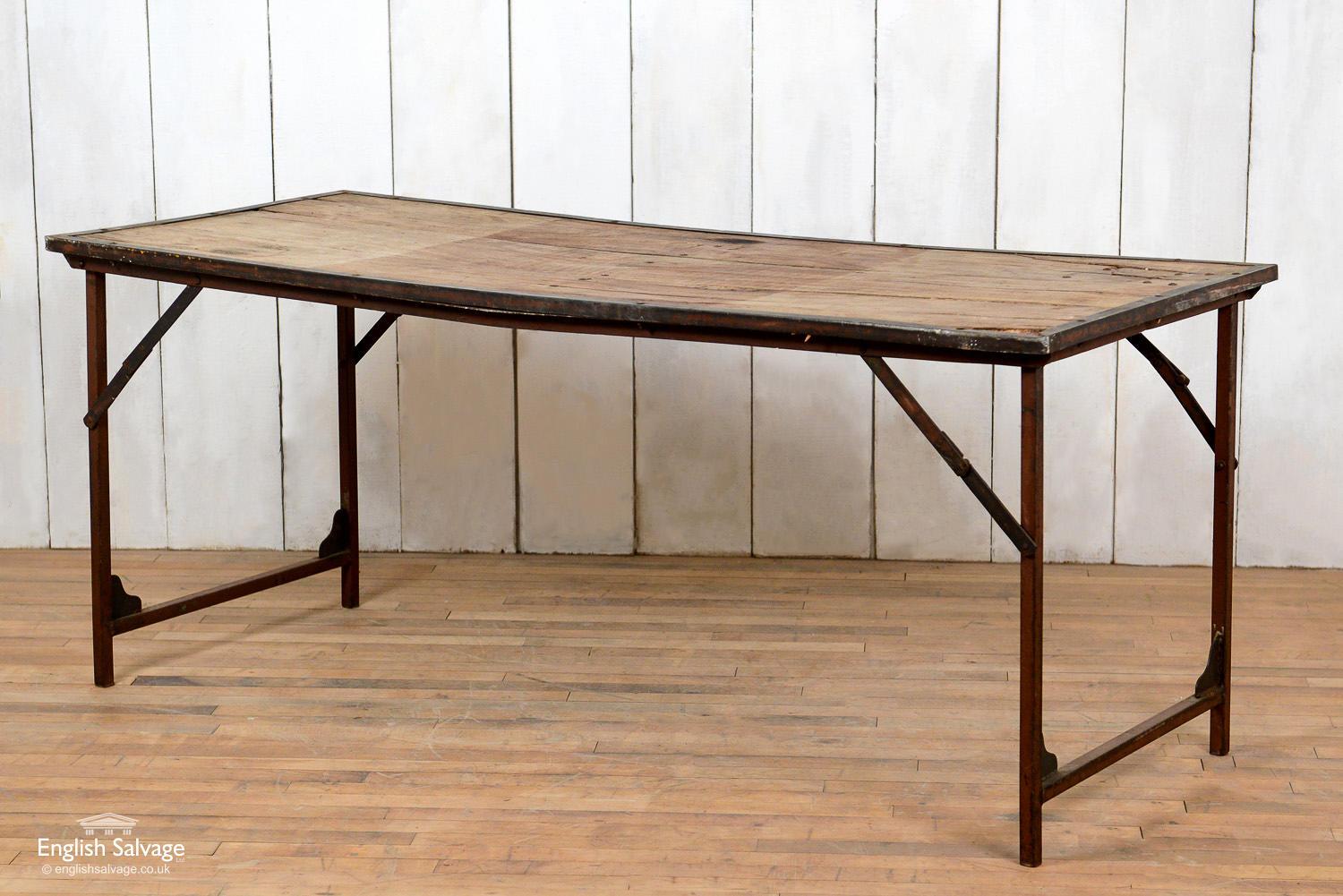 Reclaimed iron and hardwood folding table. Beautiful rustic patina to the wood with some splits and knots. Slight bow to the table and one corner missing some wood.