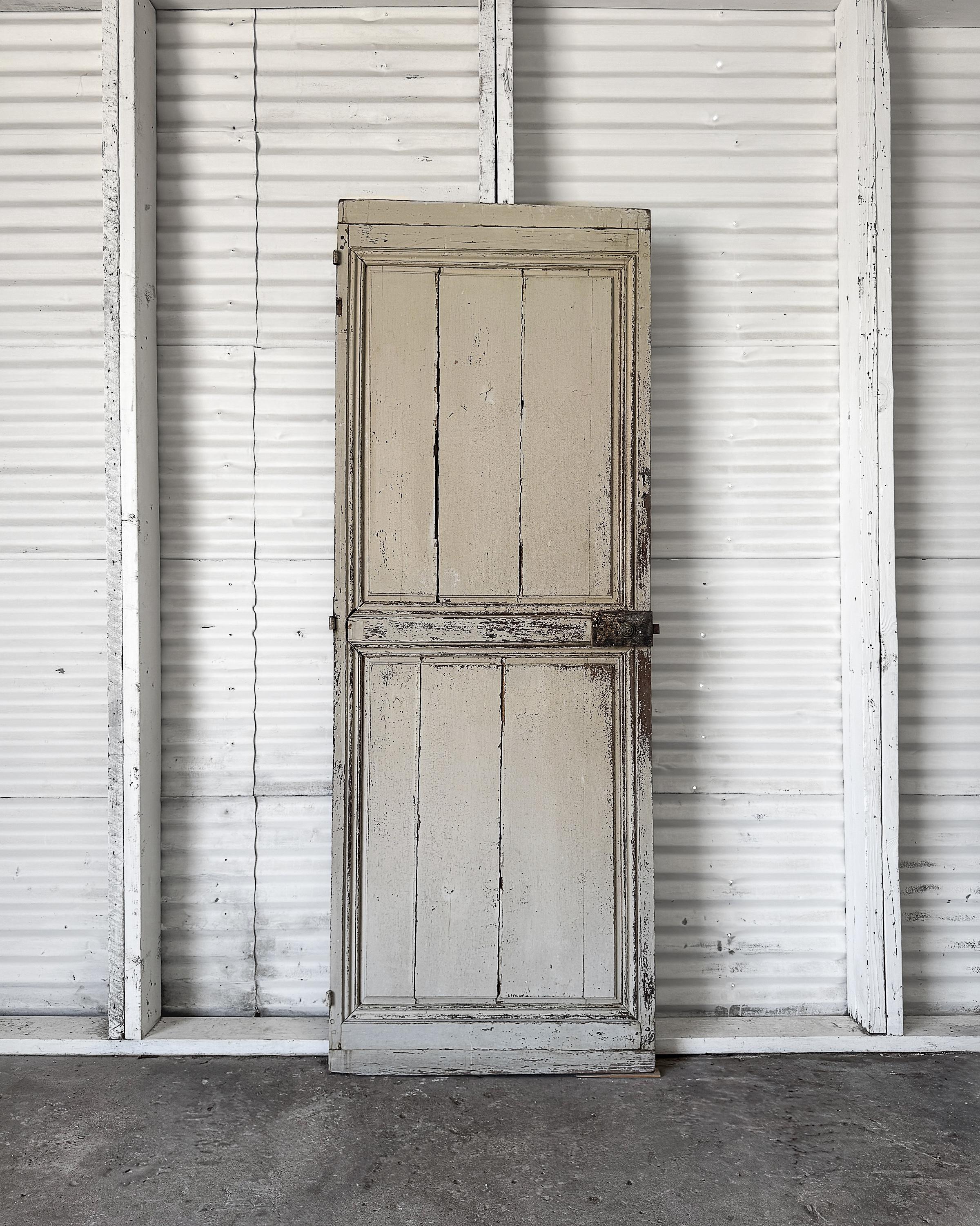 Direttamente dalla campagna francese, questa porta antica a due pannelli porta l'onesta usura del tempo. Realizzata in legno massiccio di quercia e conservando tracce della vernice originale a strati bianchi e crema, la superficie si è degradata in