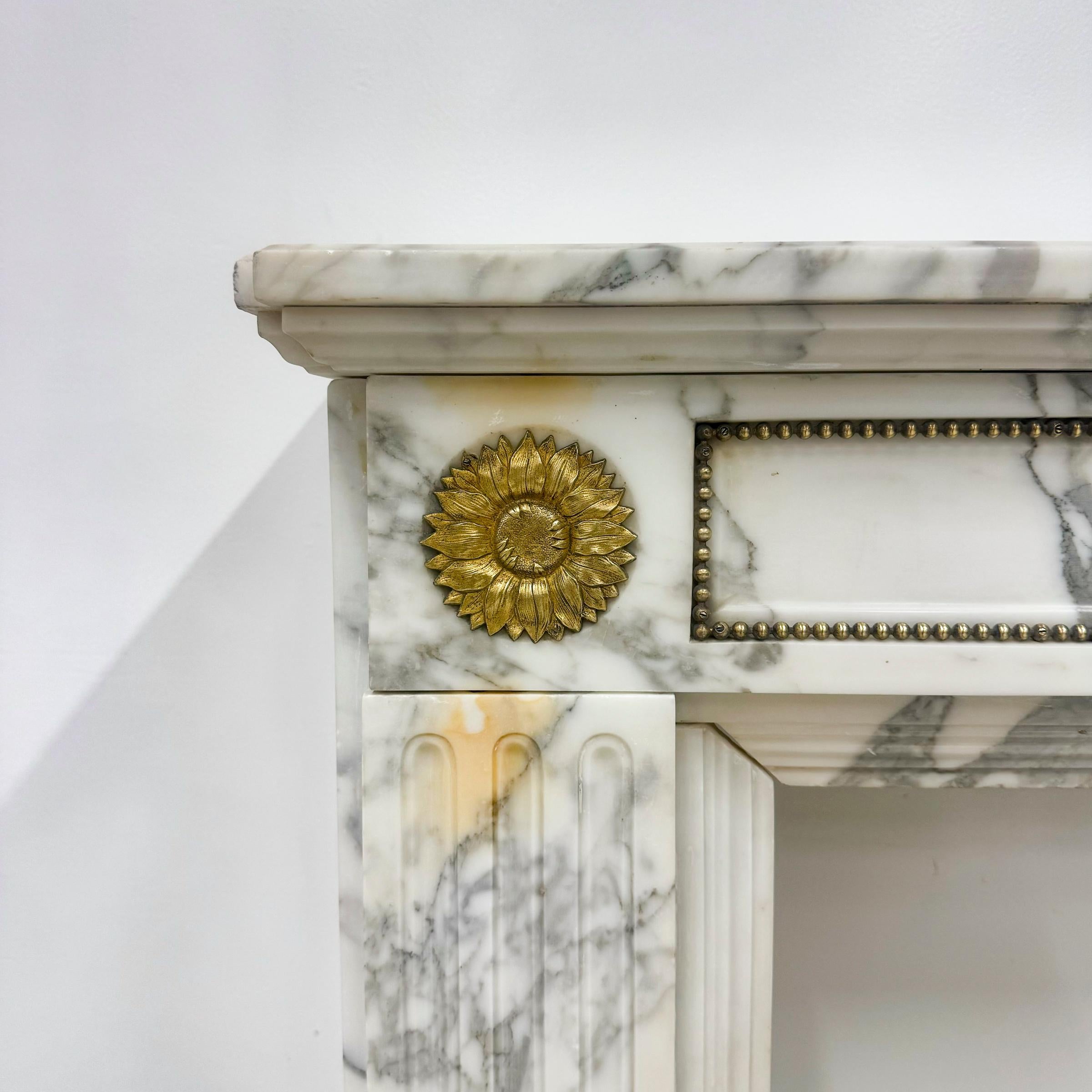 Diese Kaminumrandung aus dem Louis XVI Jahrhundert wurde fachmännisch geschnitzt und aus italienischem Marmor mit attraktiver Maserung und Ormolu-Beschlägen aus Blumenmessing gefertigt.

Dieser Kamin verfügt auch über detaillierte Messing Sicken auf
