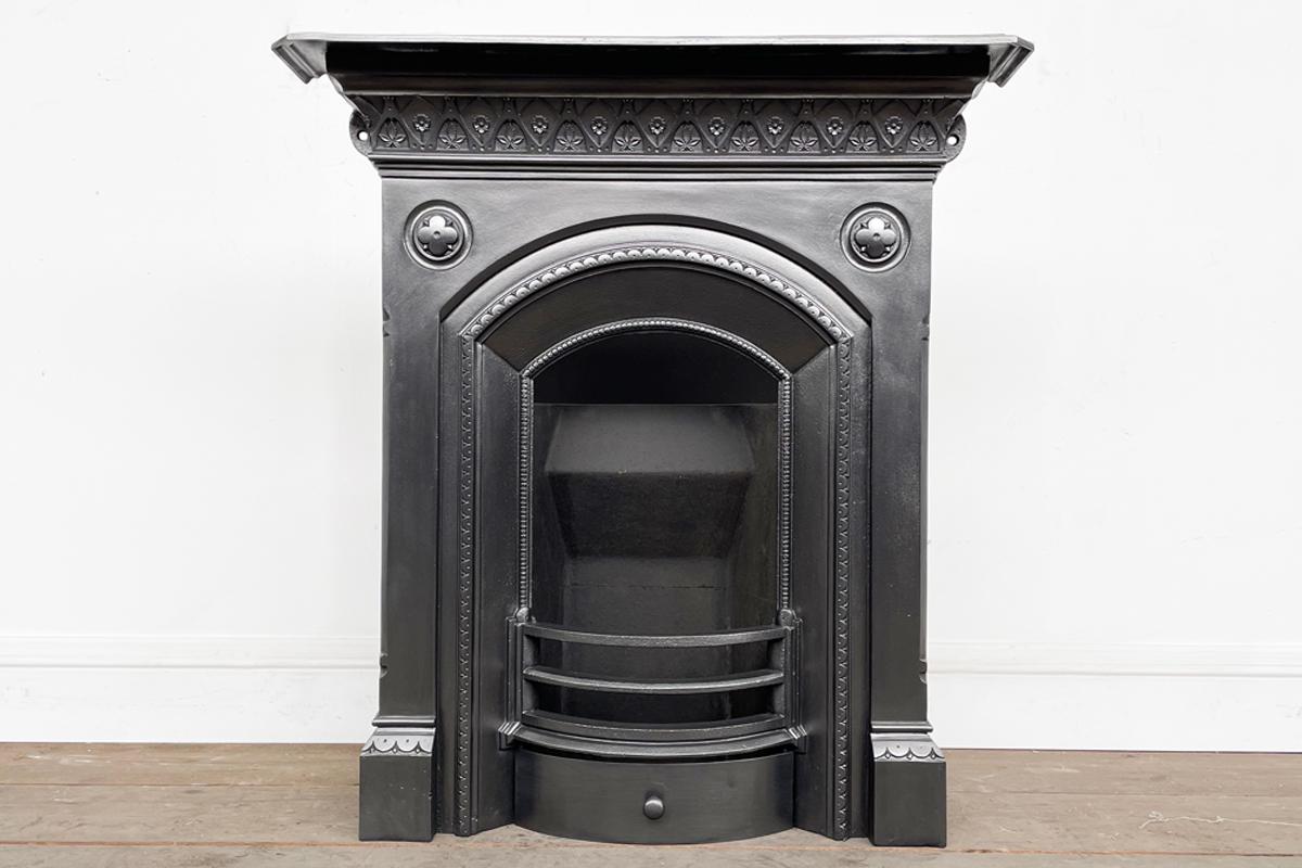 Antique mid Victorian cast iron bedroom fireplace with slow arched aperture and bosses to the spandrels. Circa 1870.

Finished in traditional black grate polish and supplied with a new clay fireback and cast iron stool grate ready for a solid fuel