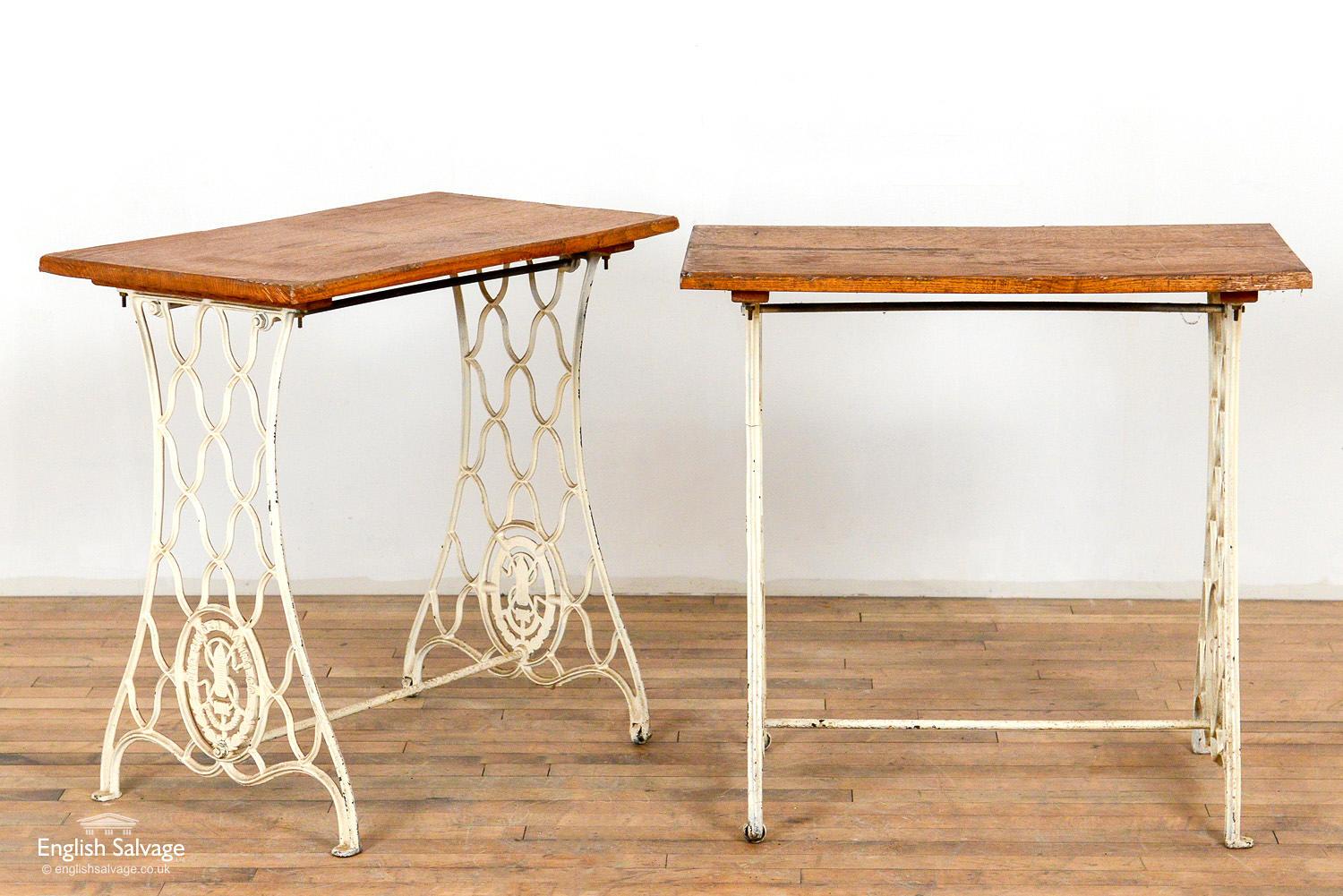 White painted metal and wood tables made from singer bases. Scrapes and scuffs commensurate with age. One base has a small crack to the metalwork.