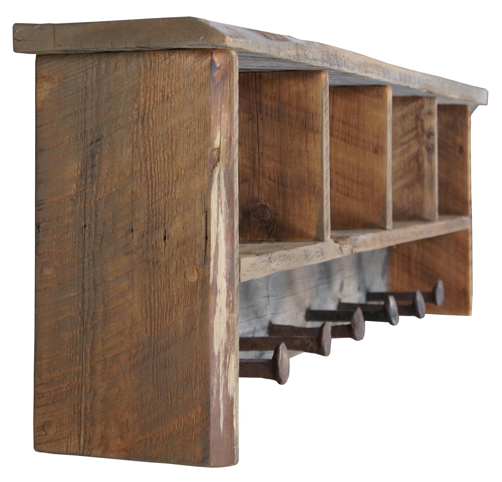 Rustic reclaimed pine wall shelf. Handmade in Aspen Colorado, circa 2nd half 20th century. Features four cubbies and railroad spikes as hooks for garments. Signed along the back.

Measures: 46