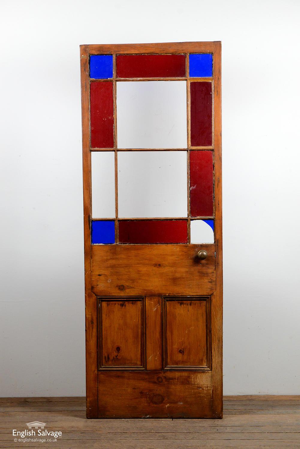 Panelled Bristol casement pine door with multi glazed panes, the outside border having a mix of blue and red coloured glass. A few panes are missing, split to lock rail and dings to edges.