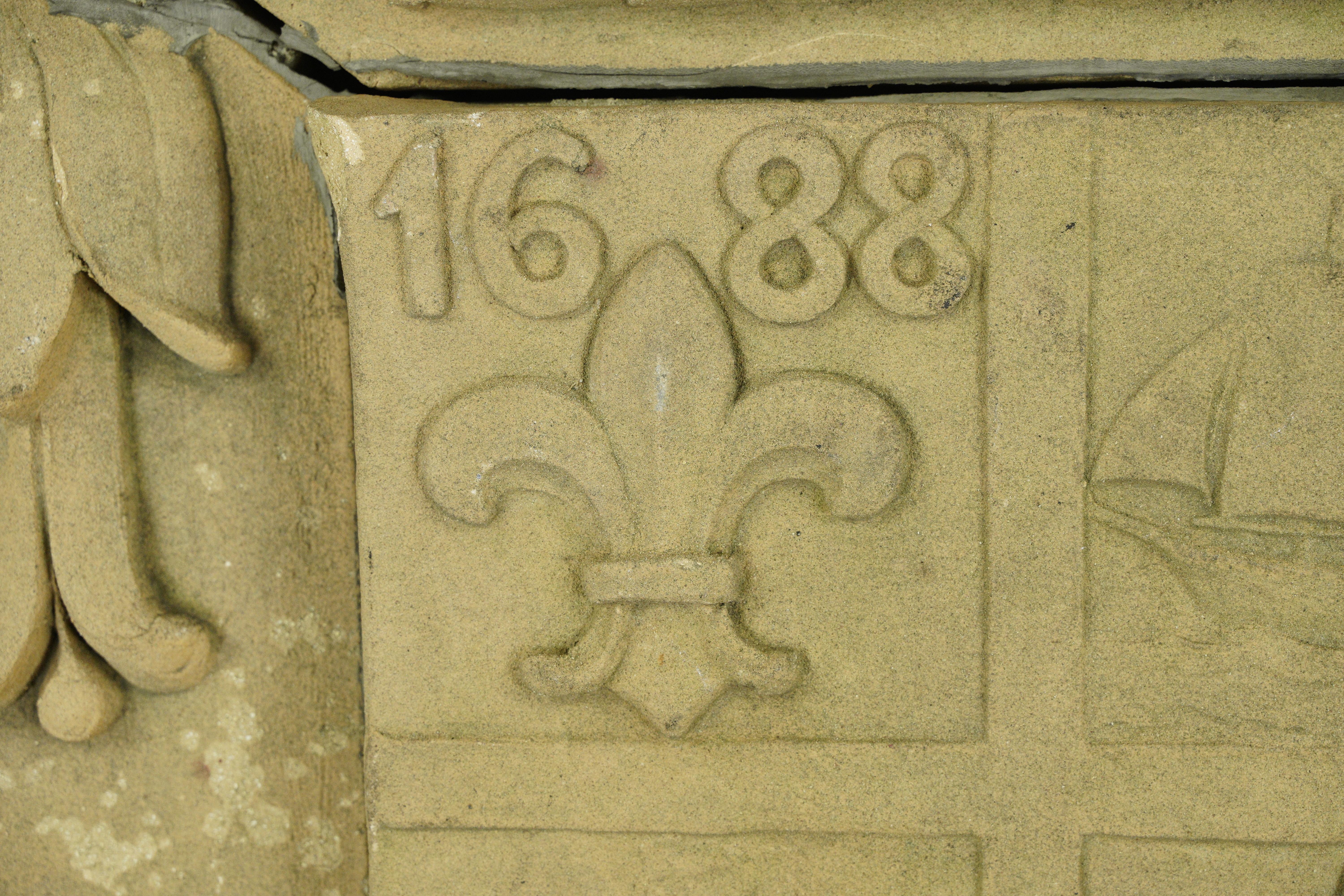 Reclaimed architectural terra cotta stone building medallion. It displays the seal of the city of New Rochelle in New York state. The seal features a fleur de lis with 1688, a star with 1899, and the Latin 