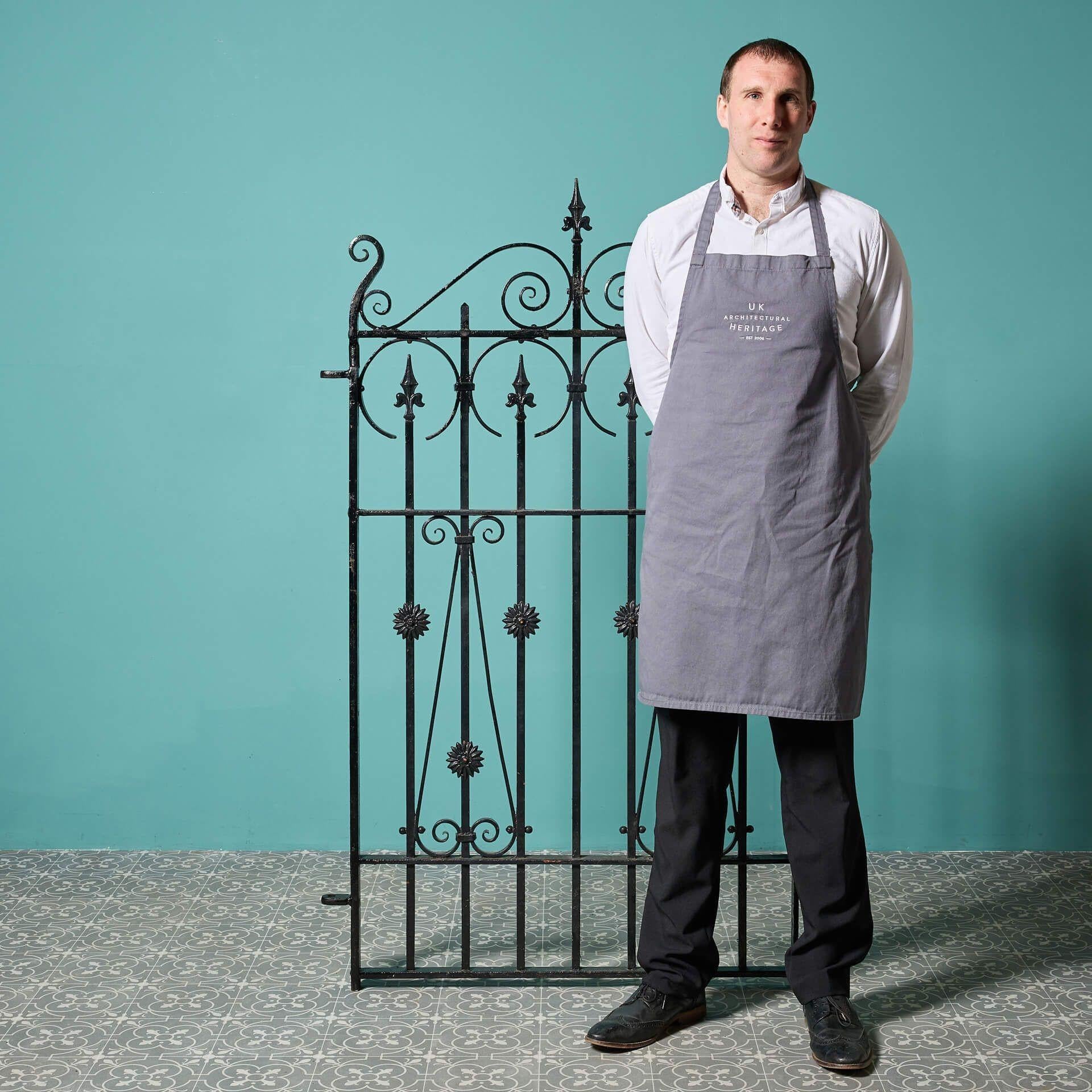 A tall and narrow early 20th century wrought iron side gate with a light rust finish. Traditionally handcrafted with a uniform pattern of scrolls and sweeping arch to the top, this smart reclaimed pedestrian gate offers timeless style for gardens