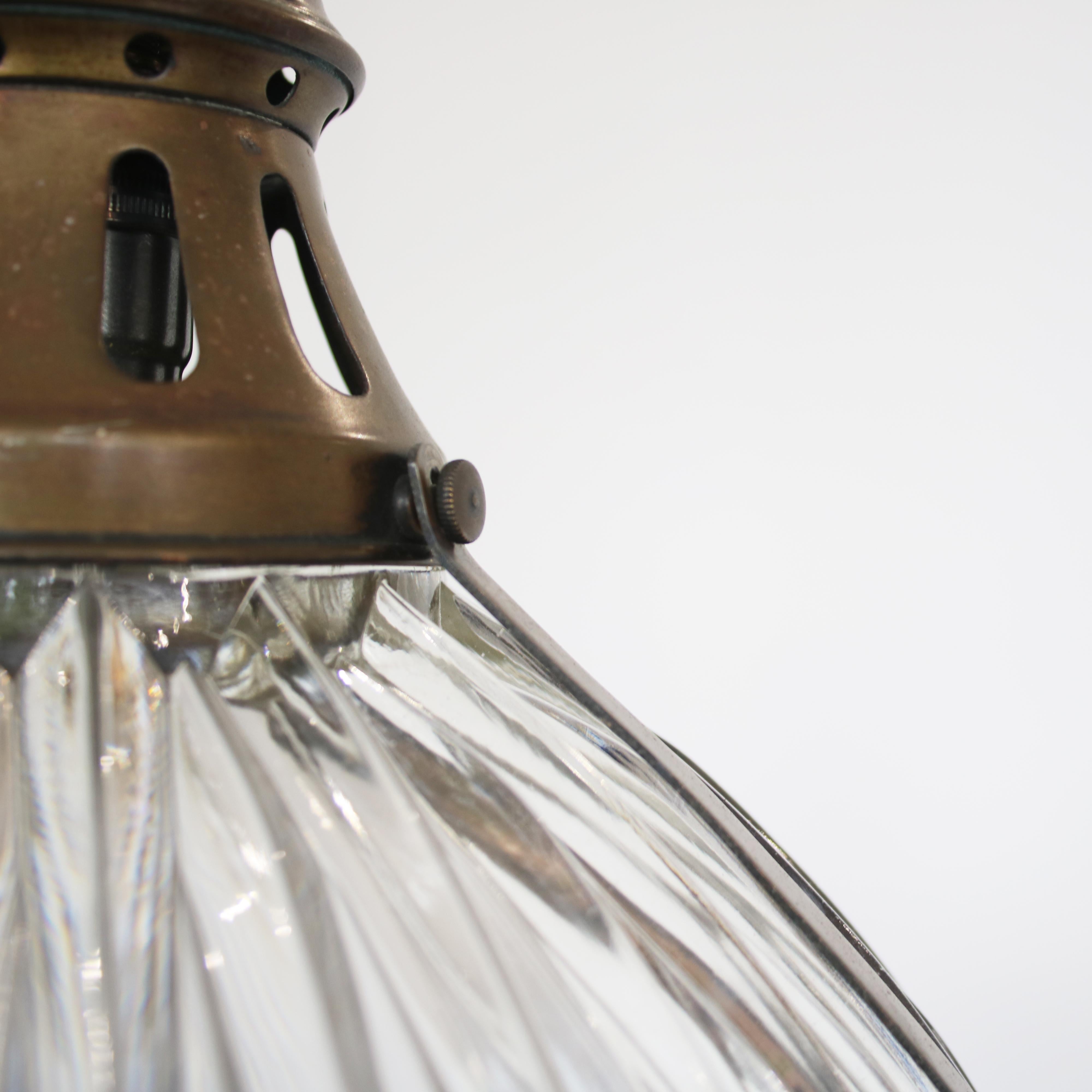 Reclaimed vintage holophane pendant light, circa 1910. The prismatic glass reflects the light beautifully. The brass gallery and supports show a wonderful patina.

Measures: 32cm diameter and 28cm high with 1m of replacement chain and ceiling