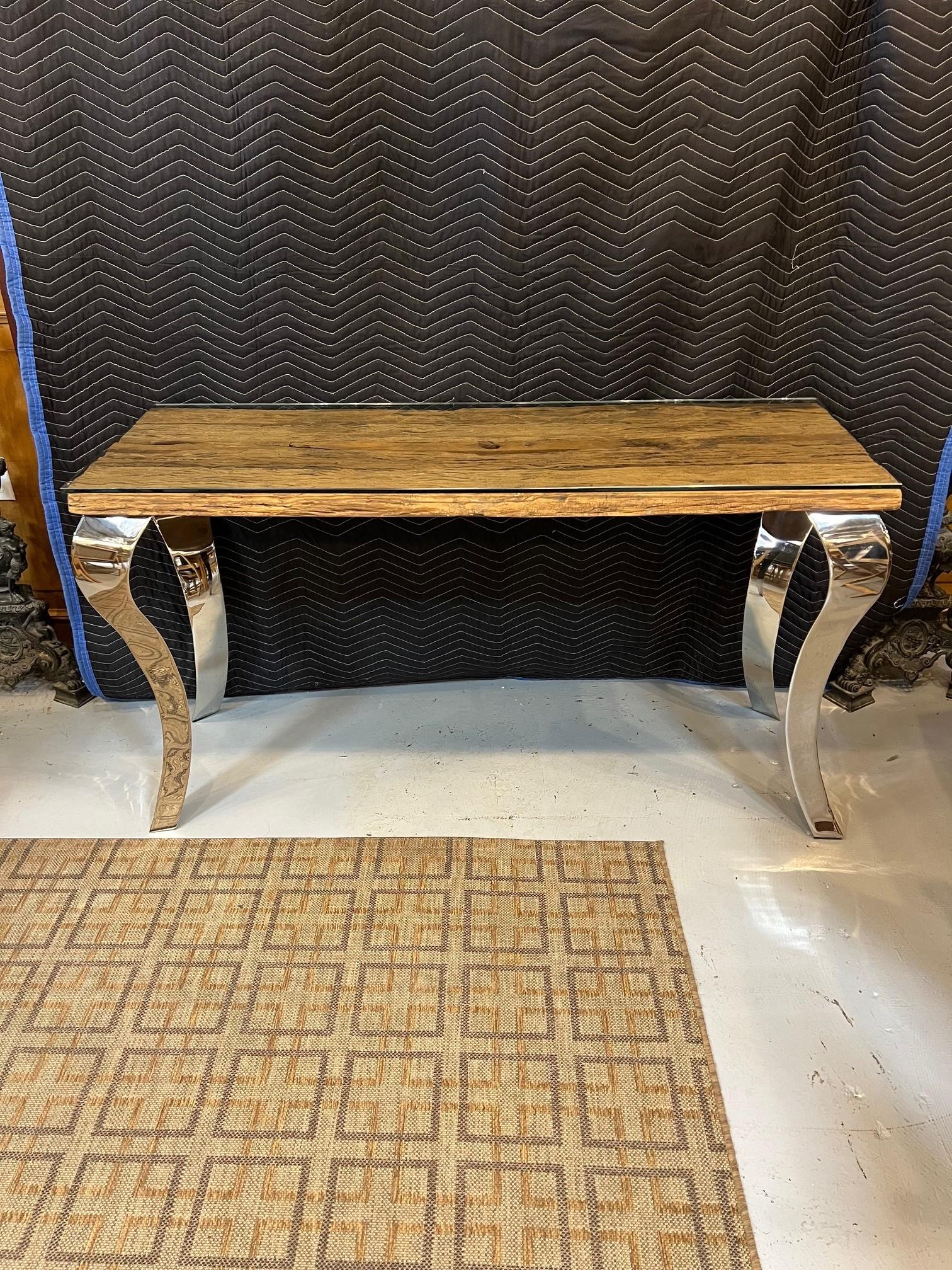 Beautiful reclaimed wood console table with a glass top and large nickel plated cabriole legs. The console table was made in India from reclaimed wood salvaged from India's railroad. The top is attached to four large plated cabriole legs. Looks