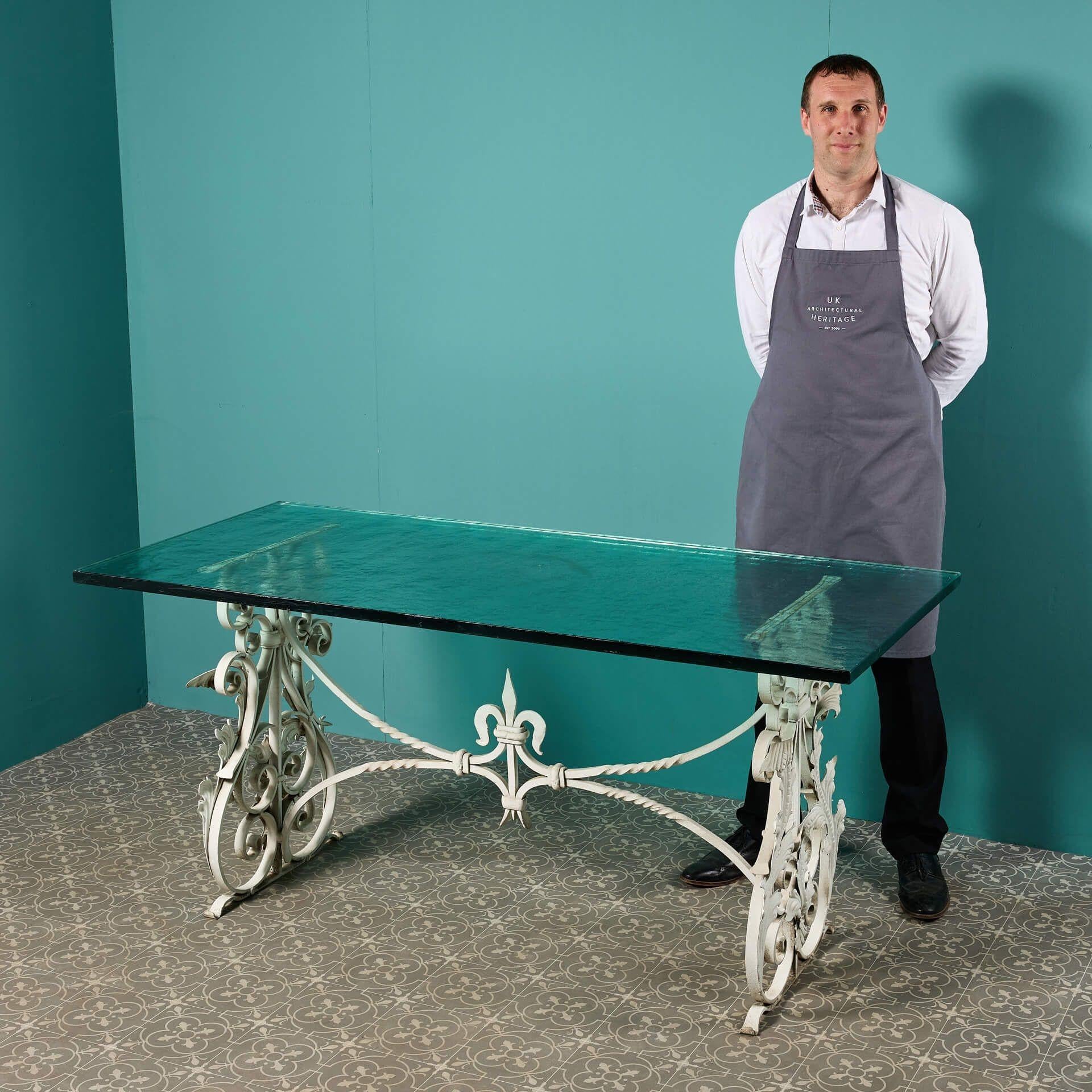 A 20th century blacksmith-made wrought iron garden table with a textured glass table top; certain to look elegant as the focal point of an outdoor dining space or patio, easily seating 4 or more. Handcrafted, the base is beautifully designed from