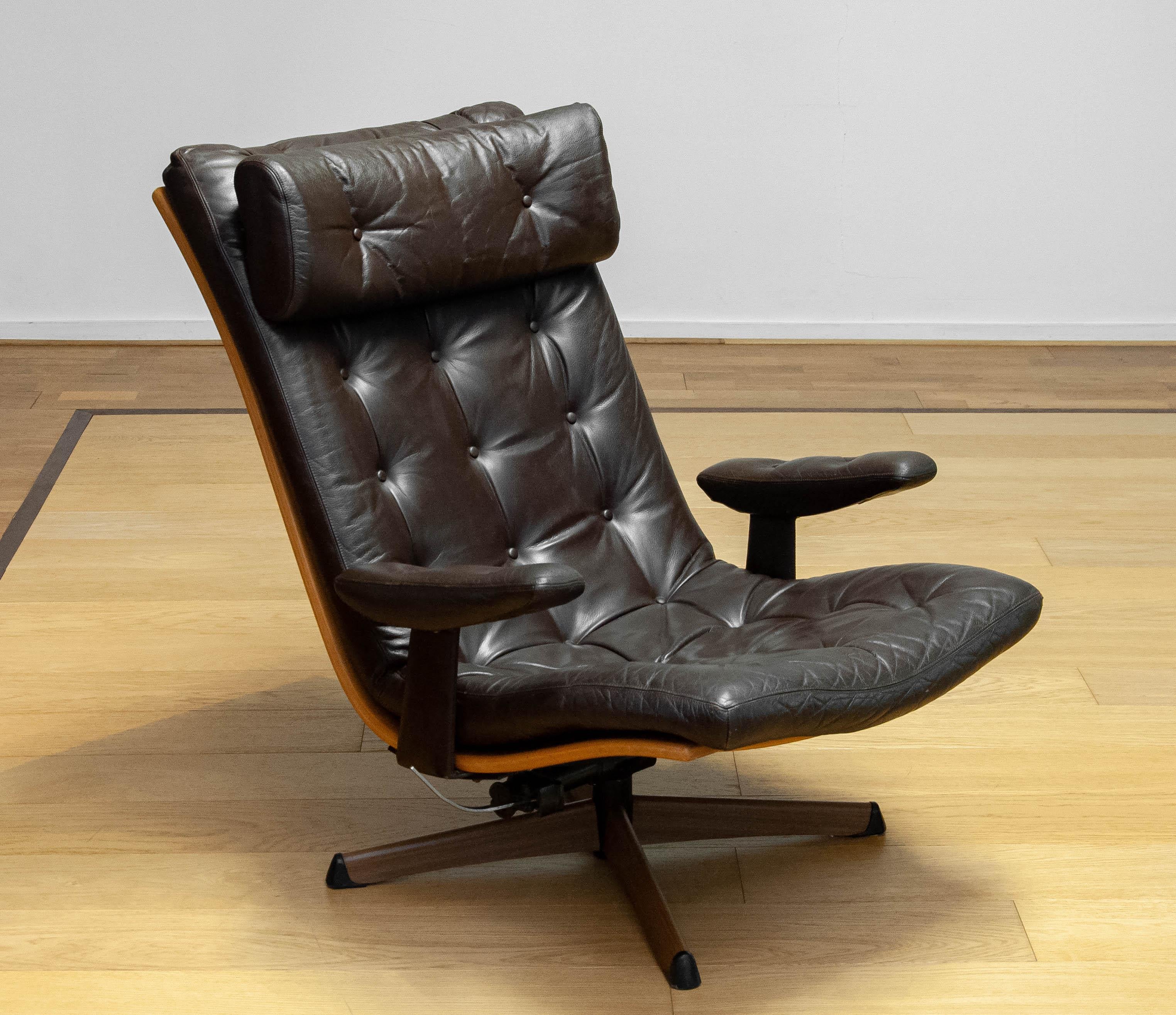 Extremely comfortable and slim recliner / lounge chair ' model: Delfin' on a swivel base from the 1960s upholstered in brown tufted leather and made by G-Design / Göte-Möbler in Nässjö Sweden.
The chair is in allover good condition and supports