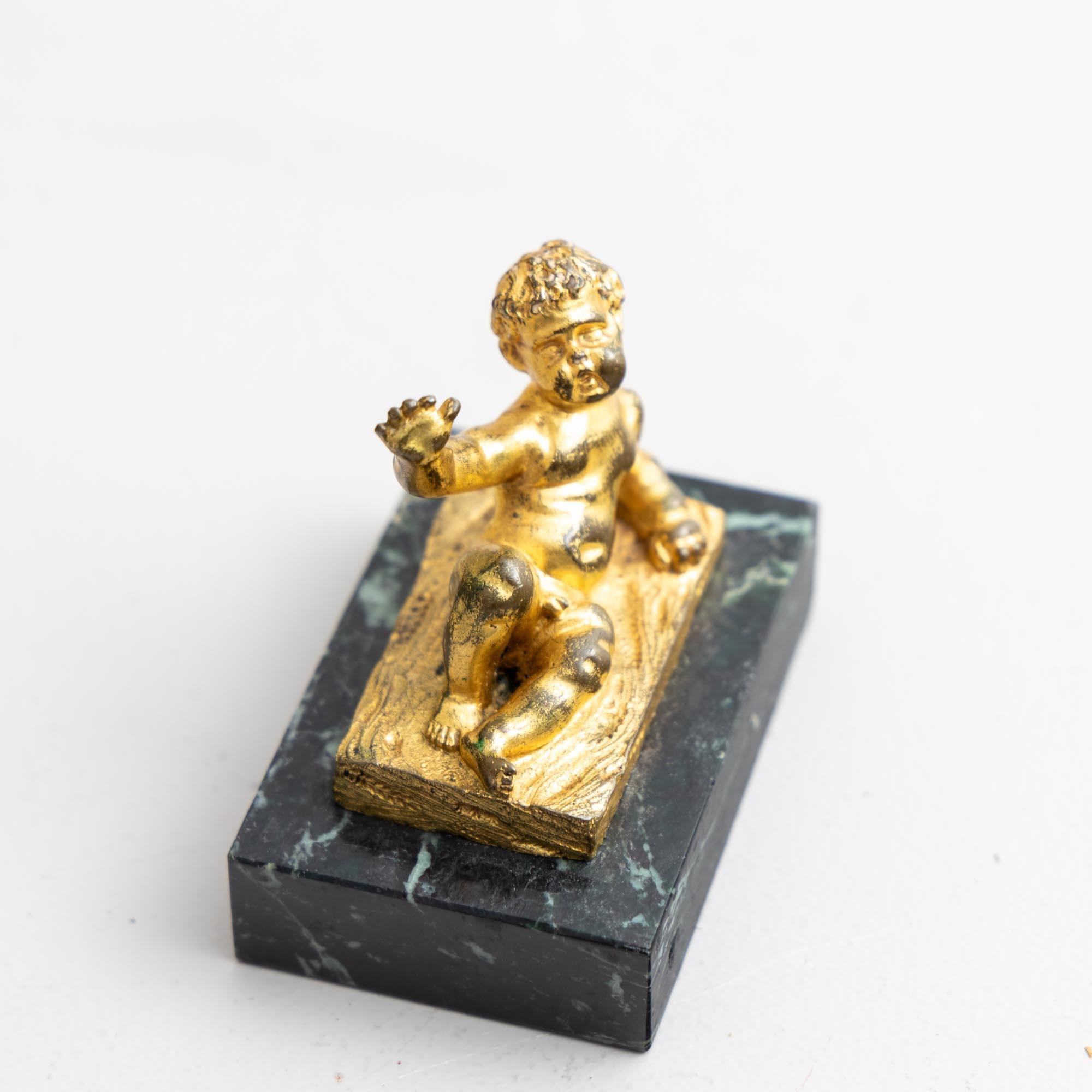 Small reclining putto of gilt bronze in an expansive gesture. The small bronze is mounted on a dark marble base. The gilding is rubbed in places.