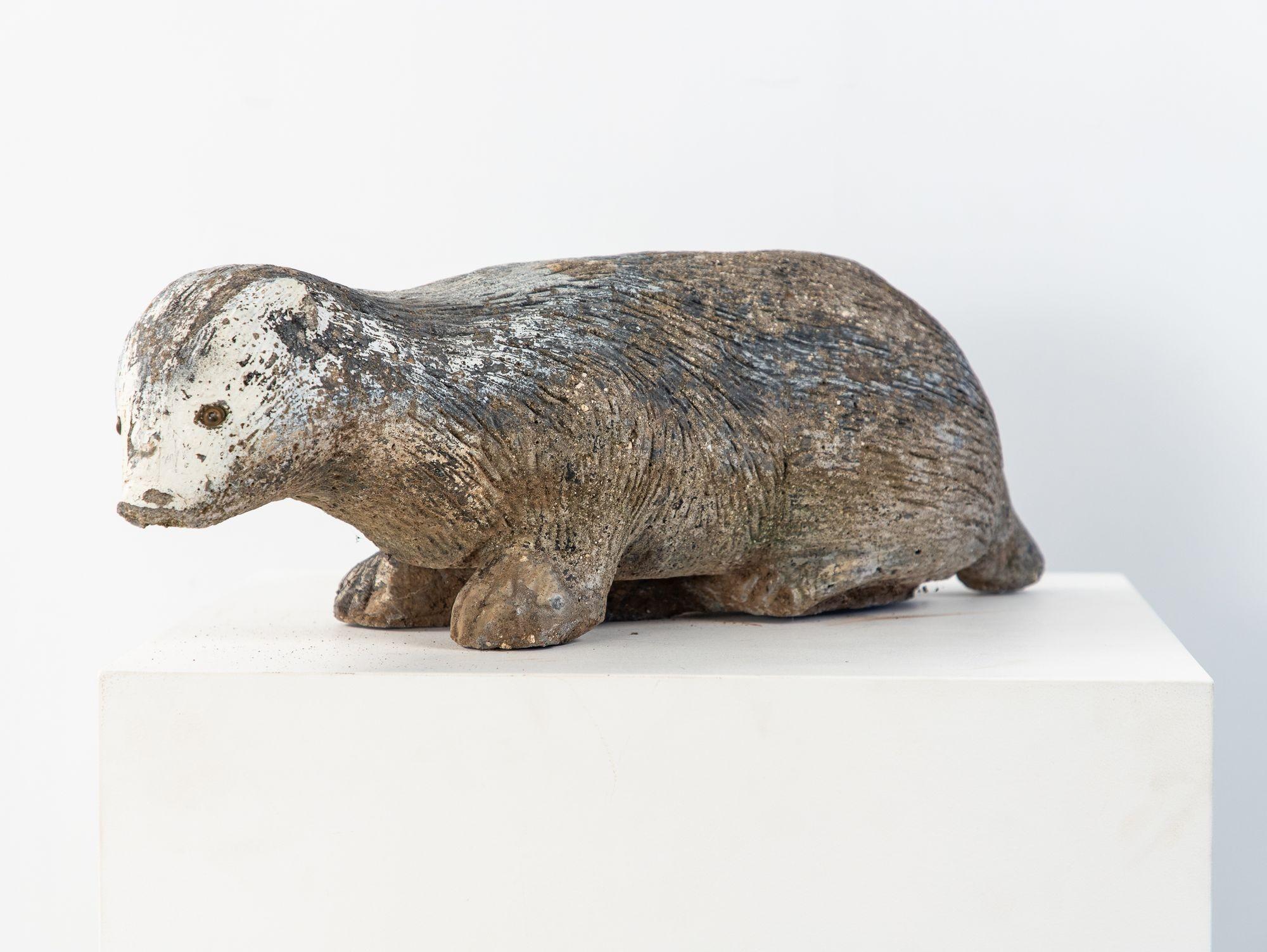 Exceptionally well-cast in composition stone, this 20th-century English garden statue depicts a badger with remarkable in-the-round modeling. The remnants of black and white paint, along with the detail in the face and body, capture the animal’s