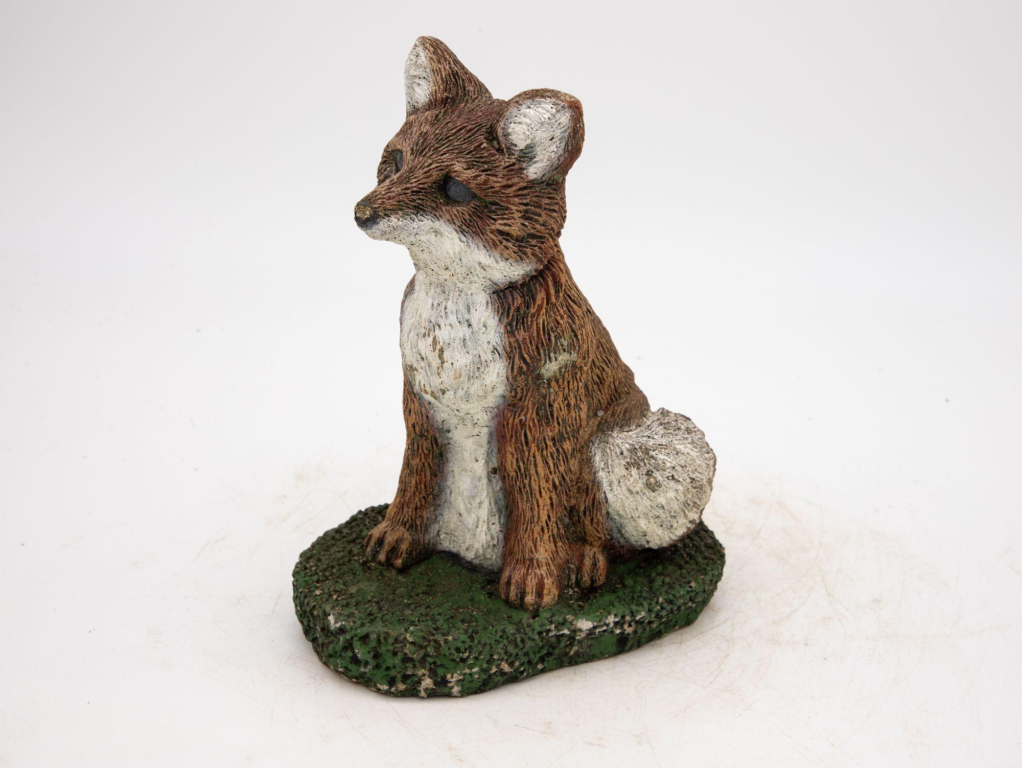 This charming fox small garden ornament is a delightful addition to any outdoor space. Crafted from durable concrete, it depicts a small fox sitting in the grass. Retaining much of the original ruddy brown, white, and green paint adds a touch of