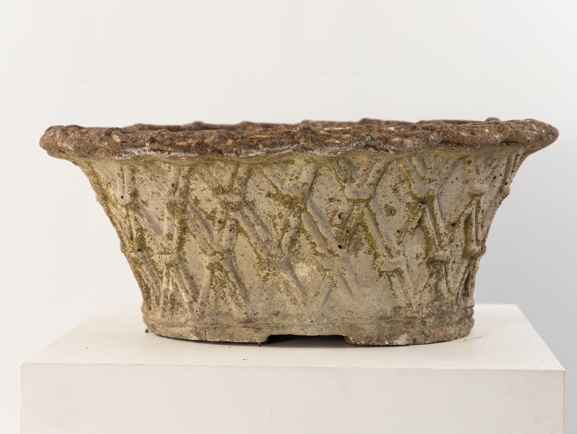 With a weathered patina and precise basket weave mould, this French mid-20th-century reconstituted stone planter adds texture and depth to any garden. The design echoes ancient techniques from woven patterns that first appeared in Egyptian reed