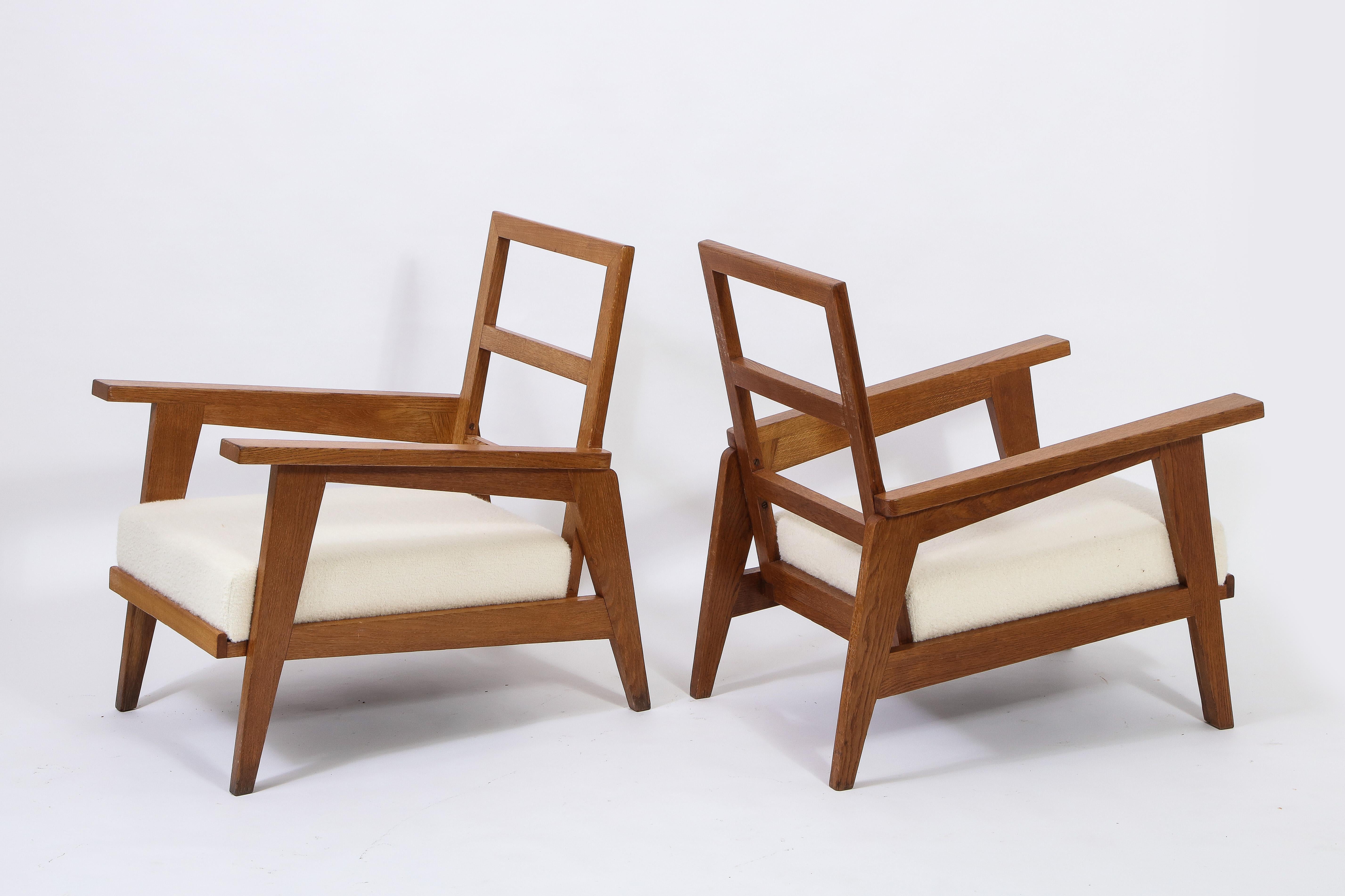 Pair of oak armchairs in the style of Rene Gabriel from the reconstruction postwar period that saw many French designers use simple lines and oak. Upholstered in boucle, custom back pillow available.