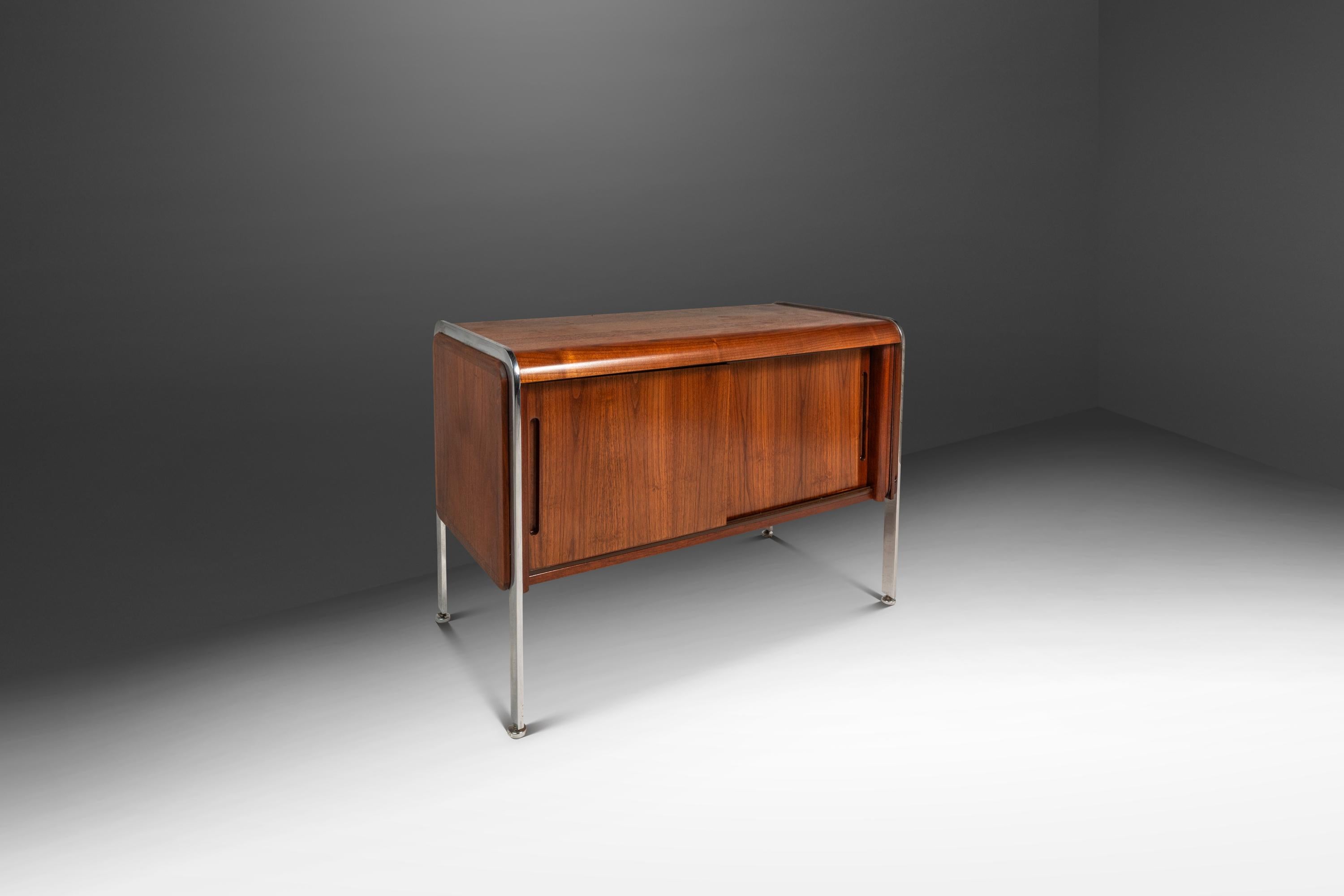 This elegant Mid-Century Modern record cabinet, inspired by the designs of Ste Marie and Laurent, showcases the refined craftsmanship of 1970s Canadian design. Constructed from teak, the cabinet features a warm, golden-brown finish that highlights