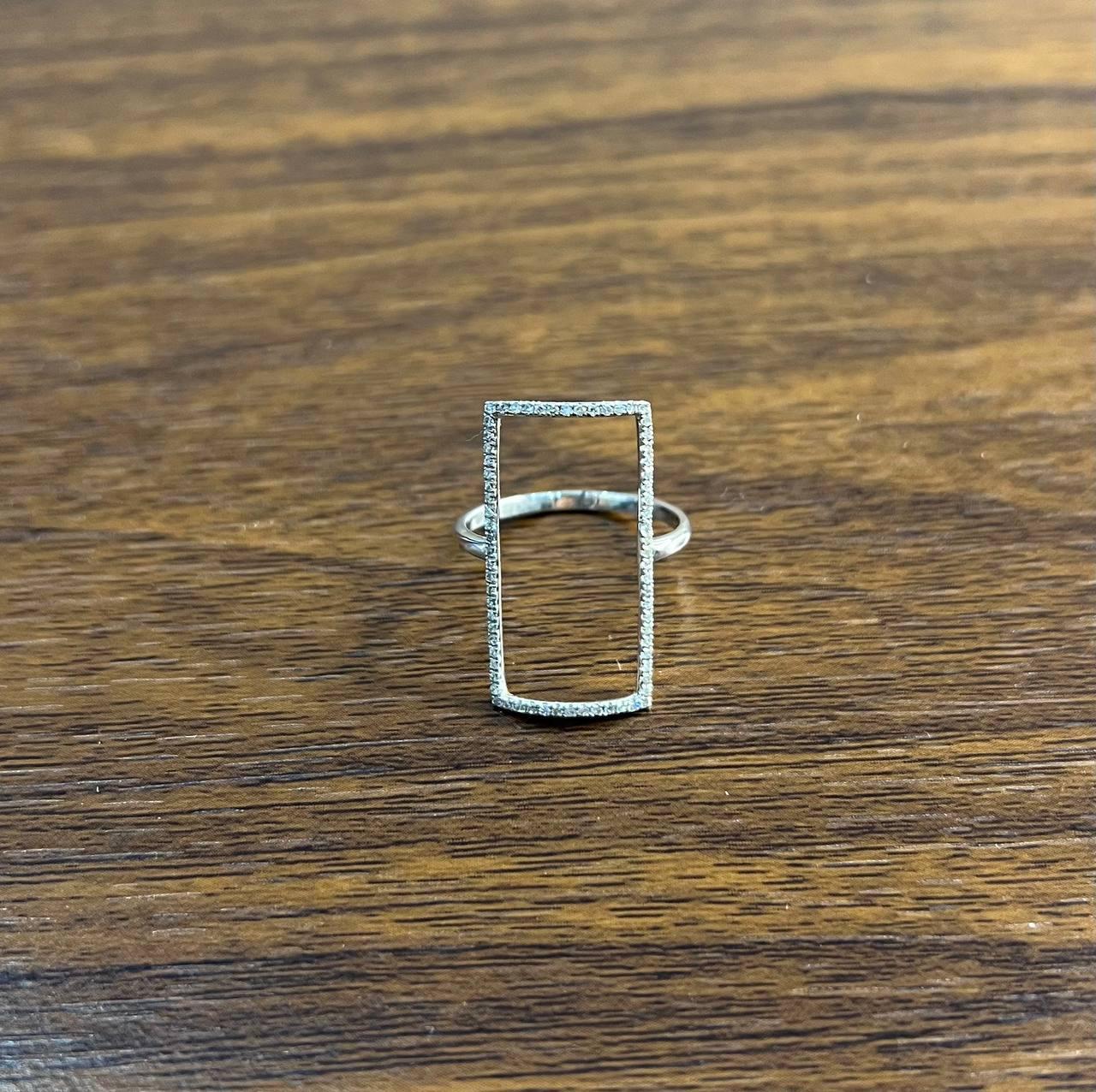 Dieses exquisite Stück zeichnet sich durch ein minimalistisches Design mit einem rechteckigen, offenen Rahmen aus, der zart mit schimmernden Steinen besetzt ist.
Die schlanke, geometrische Form sorgt für eine markante Silhouette und bietet eine