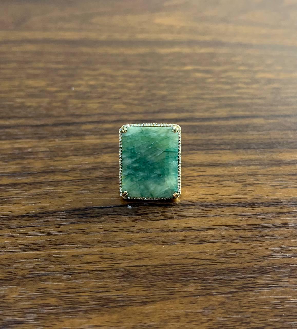 This exquisite ring features a stunning emerald-shape green sapphire as the centerpiece. The sapphire is beautifully complemented and accentuated with sparkling diamonds. Crafted in gold, the ring showcases a modern design that highlights the