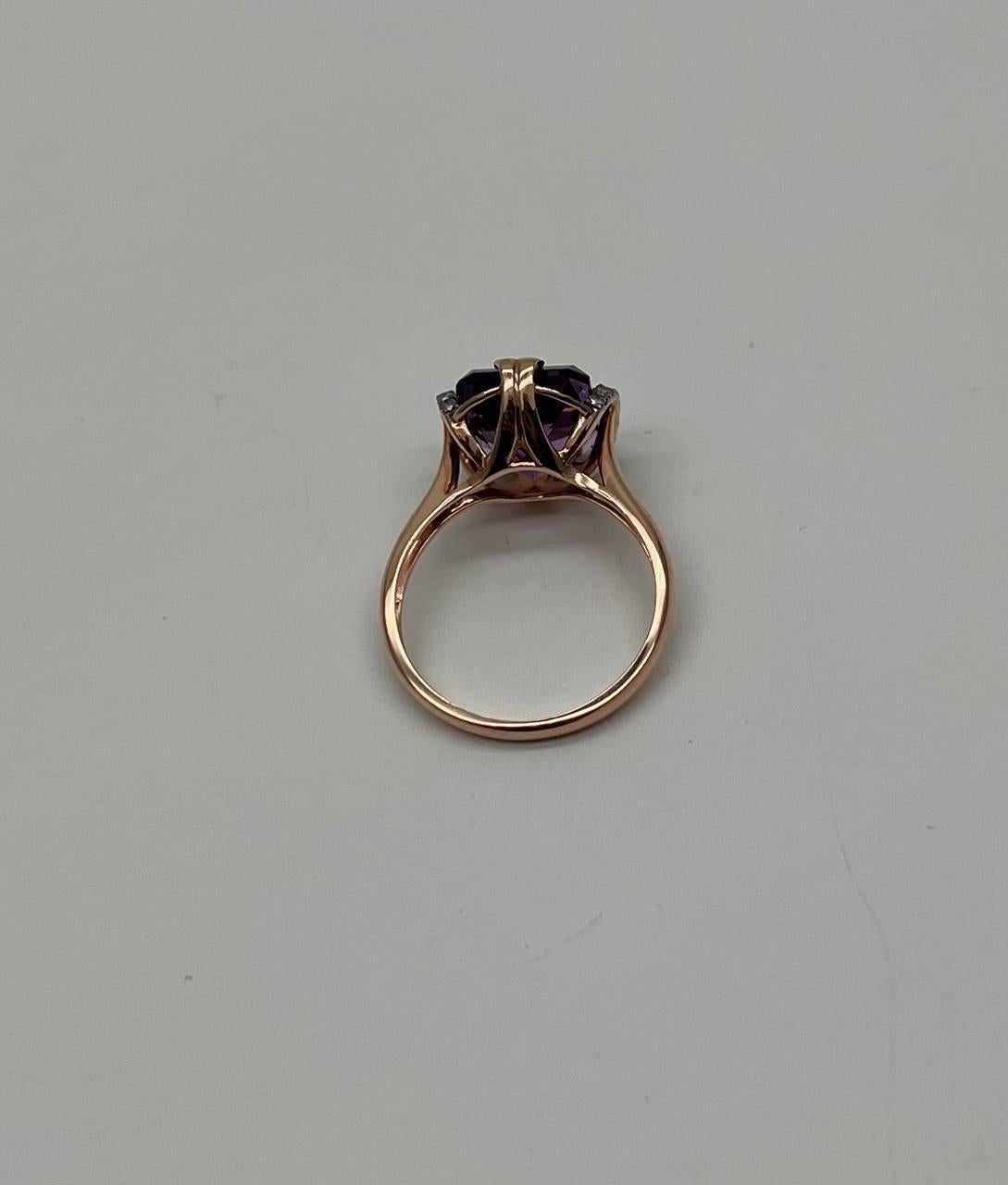 A stunning ring, features a captivating purple violet Amethyst set in a sleek rose gold band. The gemstone is elegantly held by a four-prong setting, allowing light to enhance its vibrant hue and intricate facets. The shoulders of the ring are