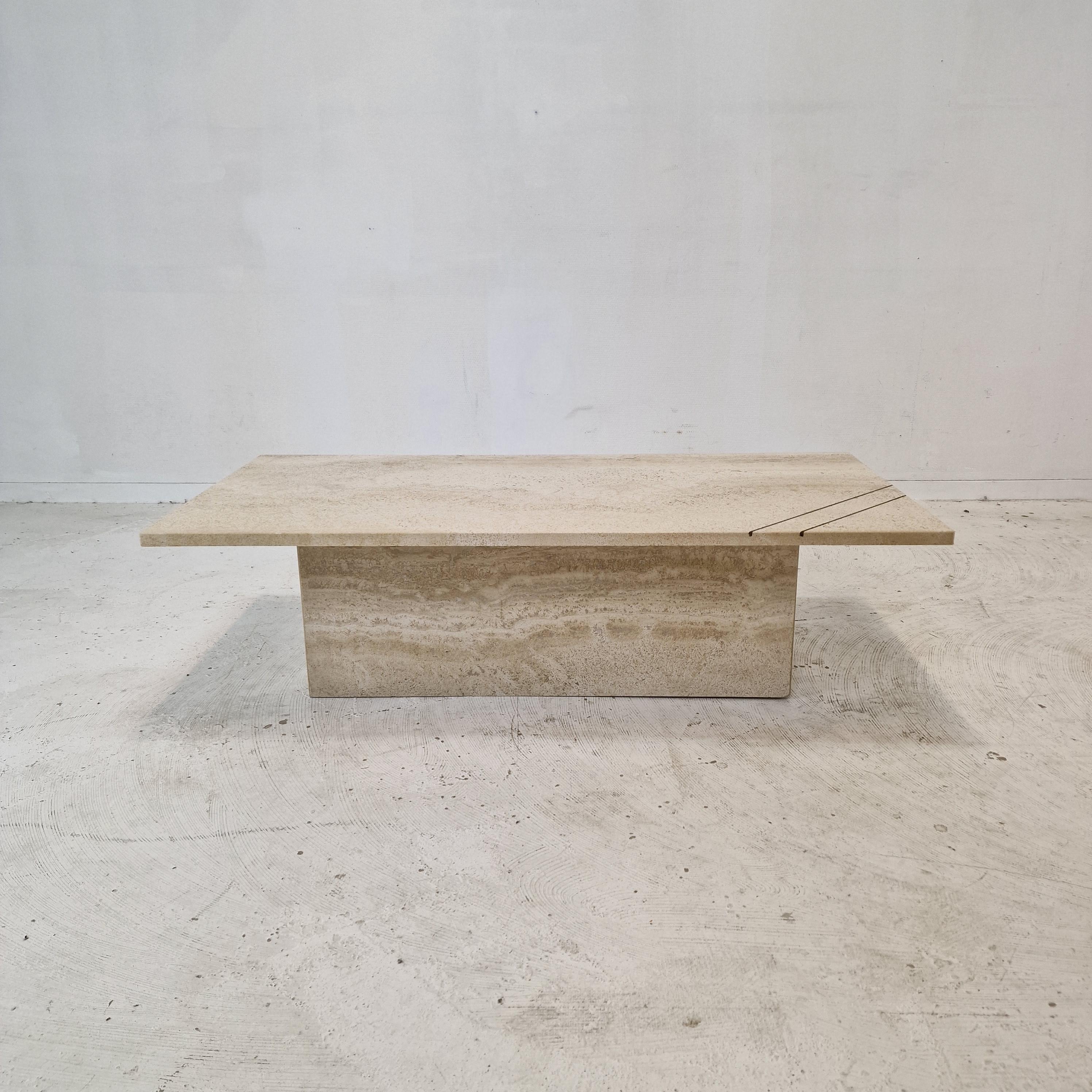 Très belle table basse ou d'appoint italienne, fabriquée dans les années 1980.
Nous l'avons trouvé dans une maison au bord d'un lac en Italie.

Elle est fabriquée à la main en très beau travertin.
La plaque rectangulaire est ornée de deux bandes de