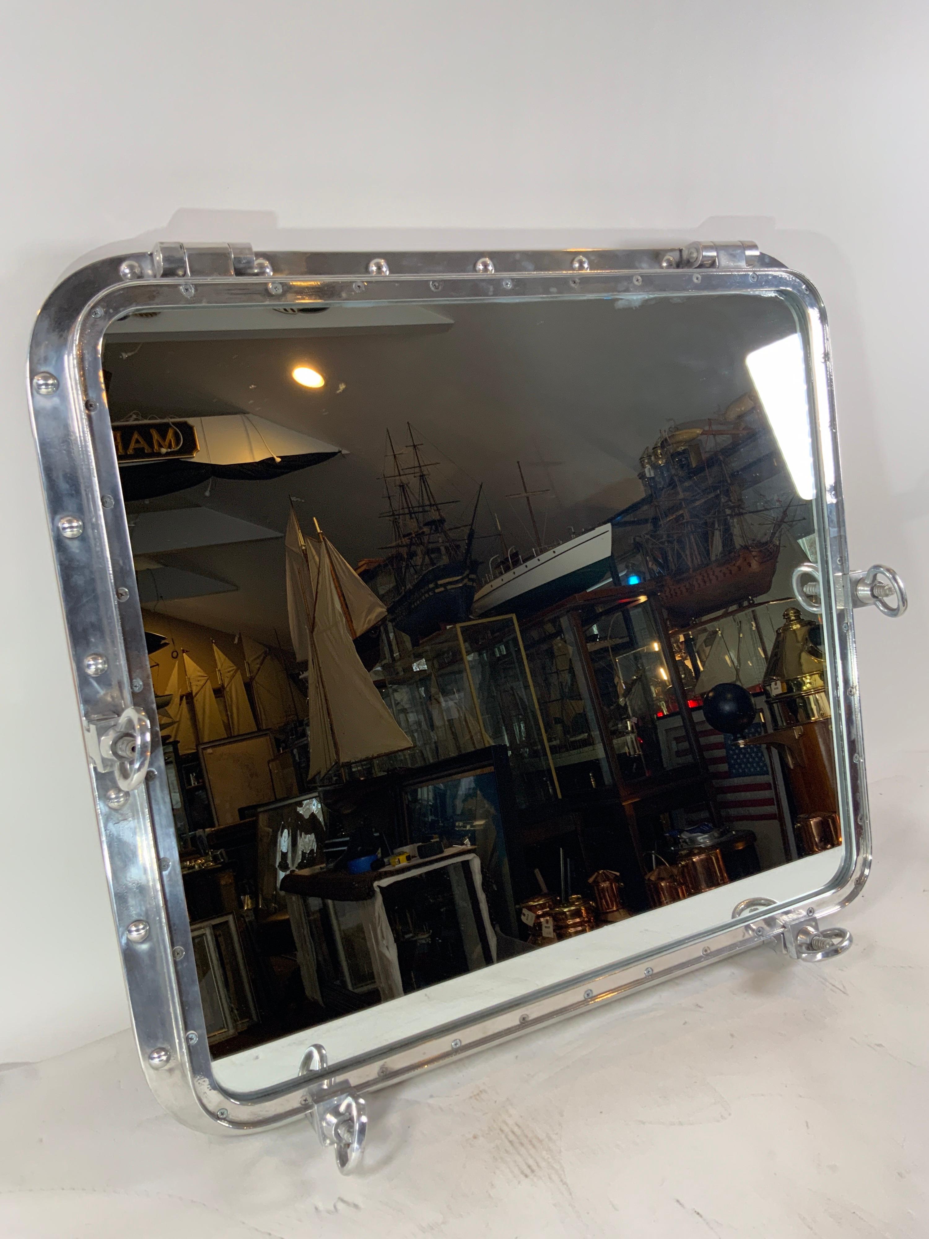 Very large highly polished aluminum ship's porthole mirror with teakwood strip around back edge. Glass mirror is fitted to frame.

Overall Dimensions: 36