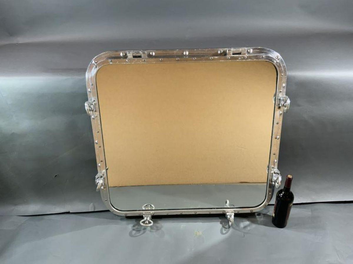 Very large highly polished aluminum ship's porthole mirror with teakwood strip around back edge. Glass mirror is fitted to frame. Overall dimensions: 36