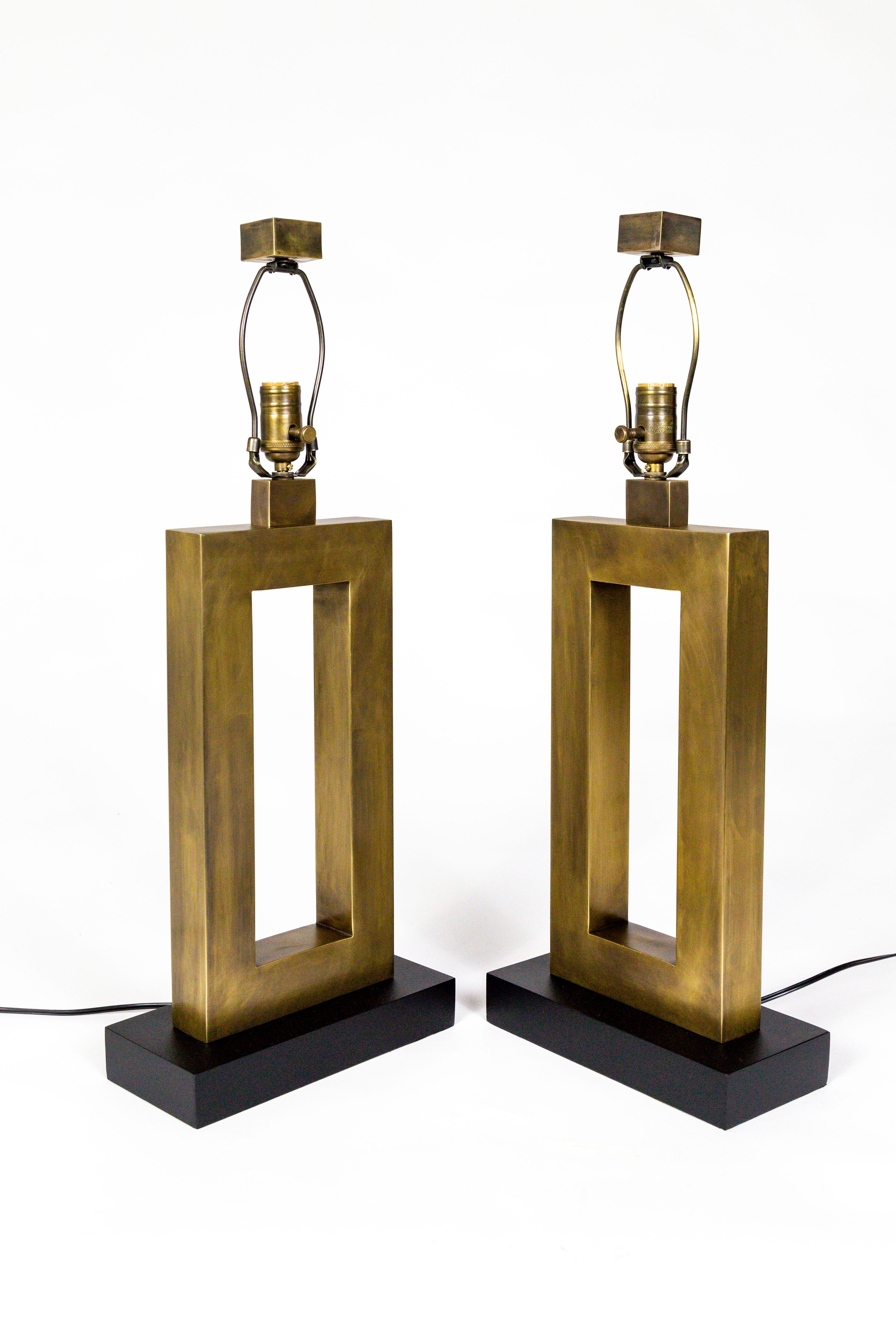 A striking pair of newly restored, 1970s antique brass, rectangular lamps; with amazingly seamless construction and flawless design. Standing on beautifully finished, black, eggshell, wood bases, and topped with complimenting square finials.