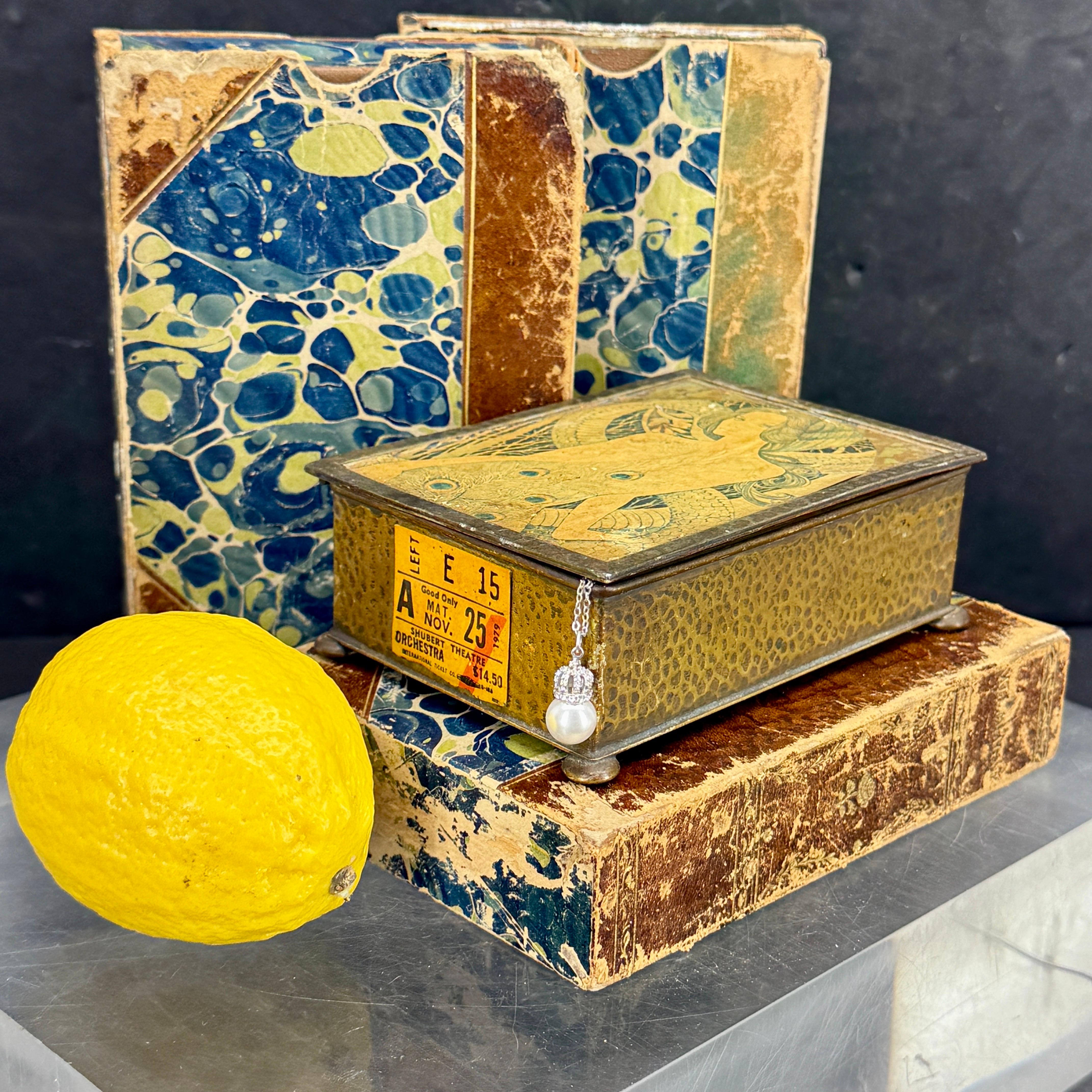 Robuste boîte à bibelots rectangulaire à charnière représentant une femme Art Nouveau portant une robe en forme de paon. Cette boîte est super charmante et fonctionnelle pour présenter ou contenir des bijoux ou autres bibelots. Merveilleuse pièce à