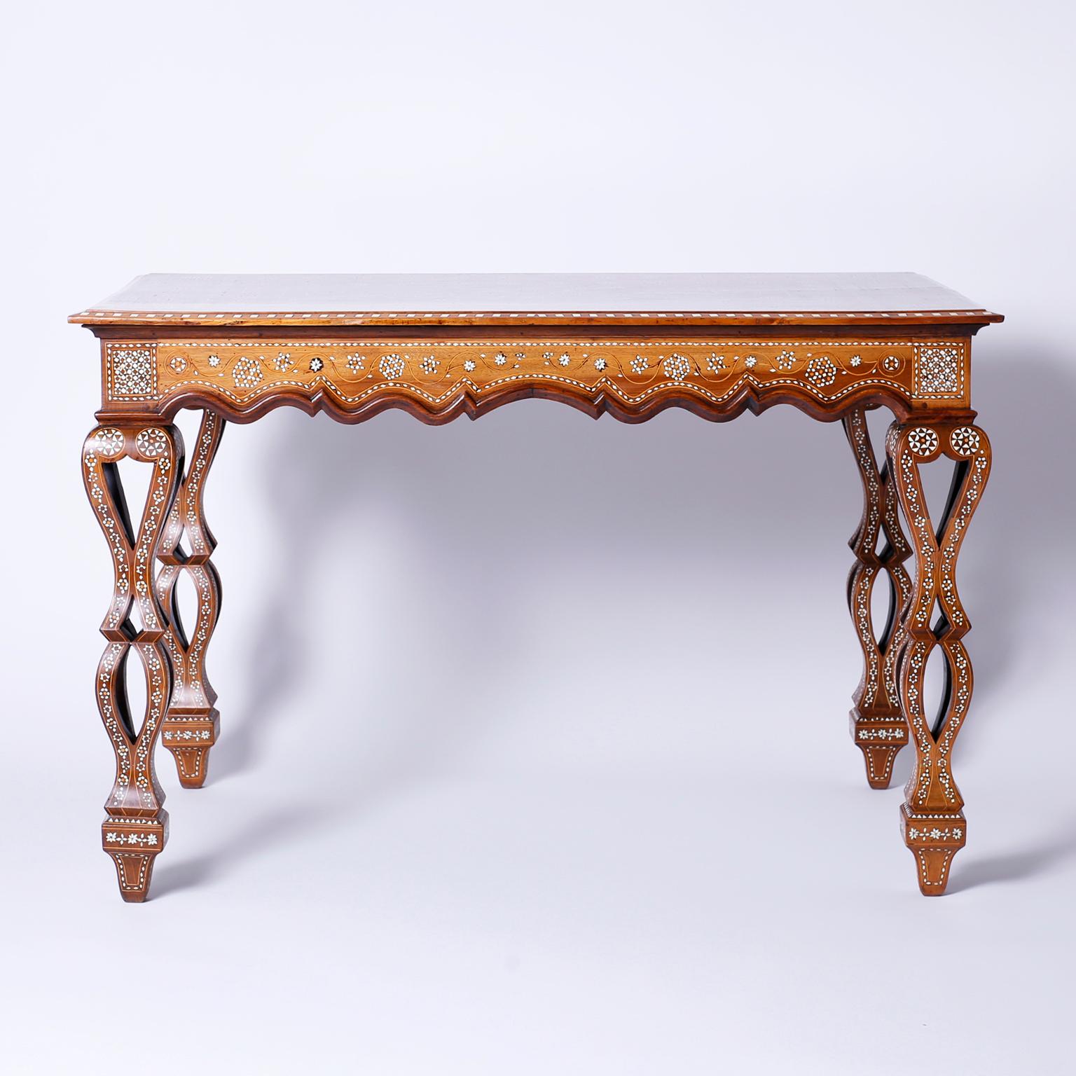 Captivating Syrian walnut center table, dining table, or writing table with a rectangular top inlaid with bone, mother or pearl, and king wood in an enchanting combination of floral and geometric designs. The skirt is scalloped and inlaid.
The