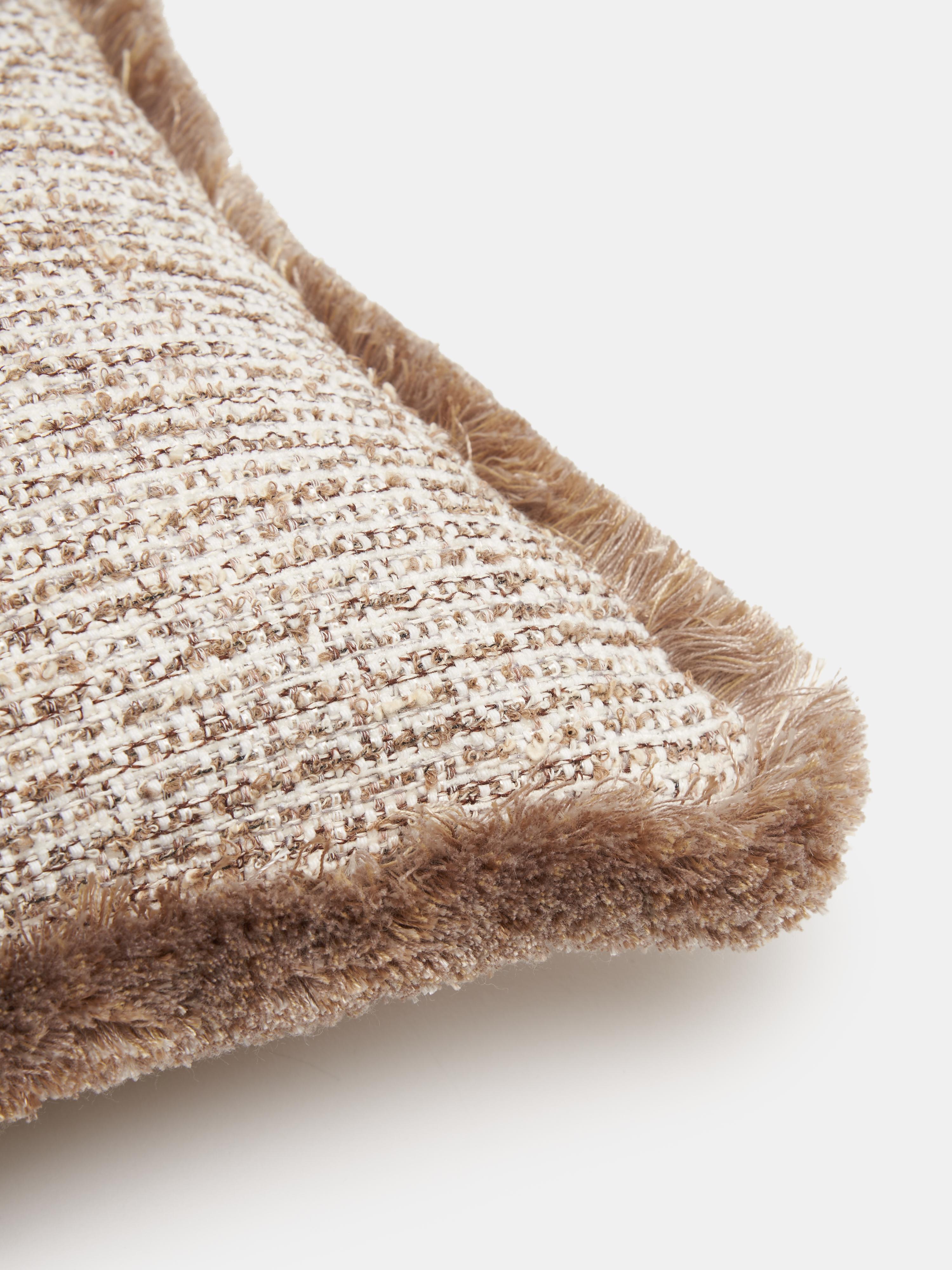 Cuscino rettangolare con frange della linea BOUCLÉ di Villa Como, realizzato a mano a Como con tessuti italiani di alta qualità. Il rivestimento presenta una trama bouclé nei toni del beige e del tortora, ricca, irregolare e piacevolmente