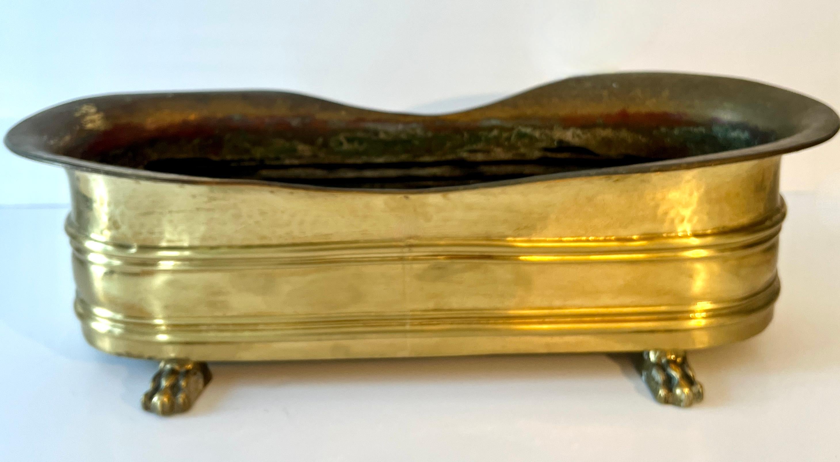 Elongated Rectangular Brass Jardiniere or planter with Lion Paw feet and a gentle curve to the front and rear sides.

A compliment to any table, outdoor or interior.  The length holds a nice assortment of plants or arranged flowers.   Also works
