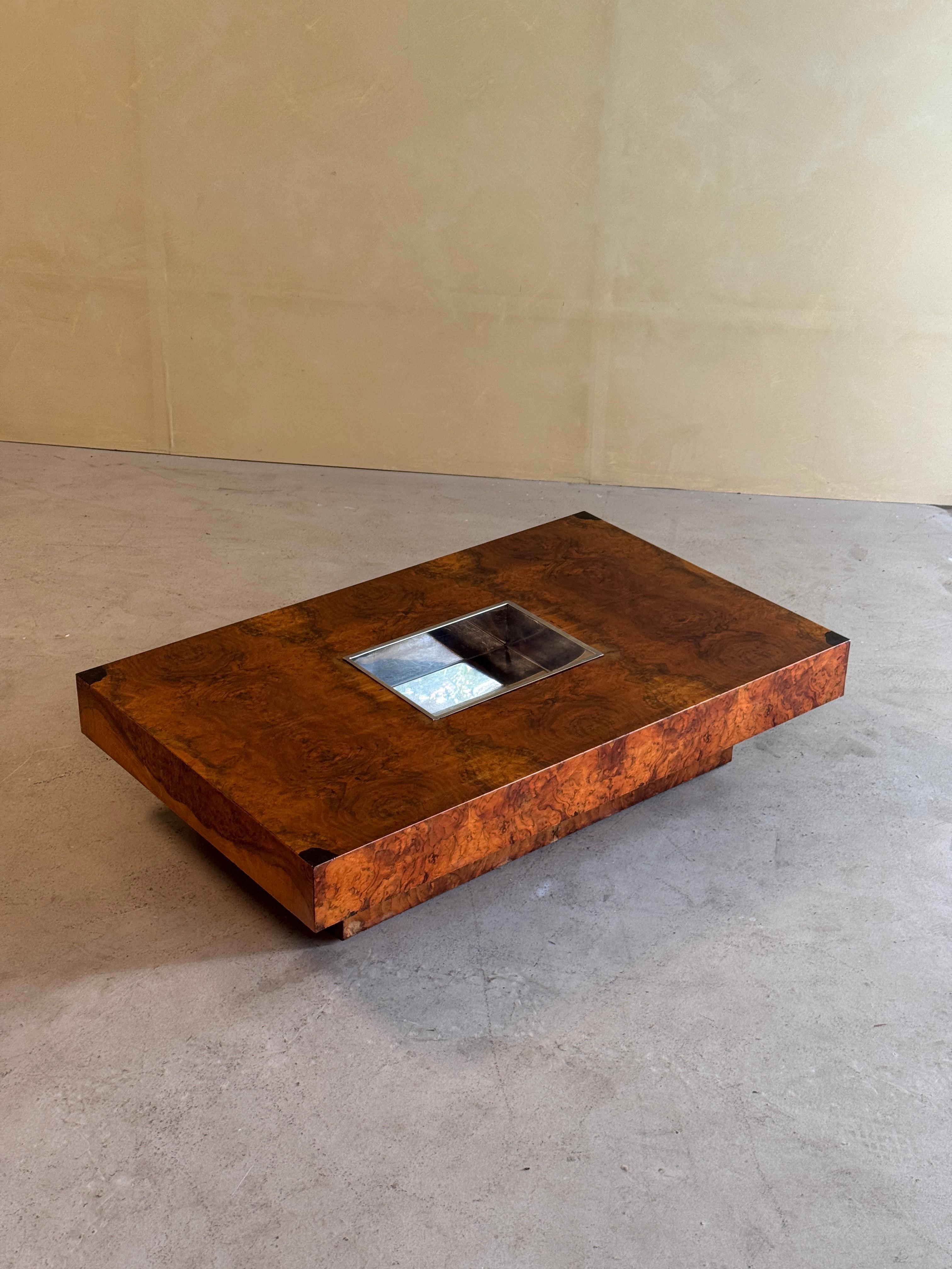 Sophisticated vintage coffee table crafted from exquisite burl wood, showcasing rich natural patterns. Its bold rectangular form is enhanced by a striking central inset in polished metal, creating a refined statement piece that embodies timeless