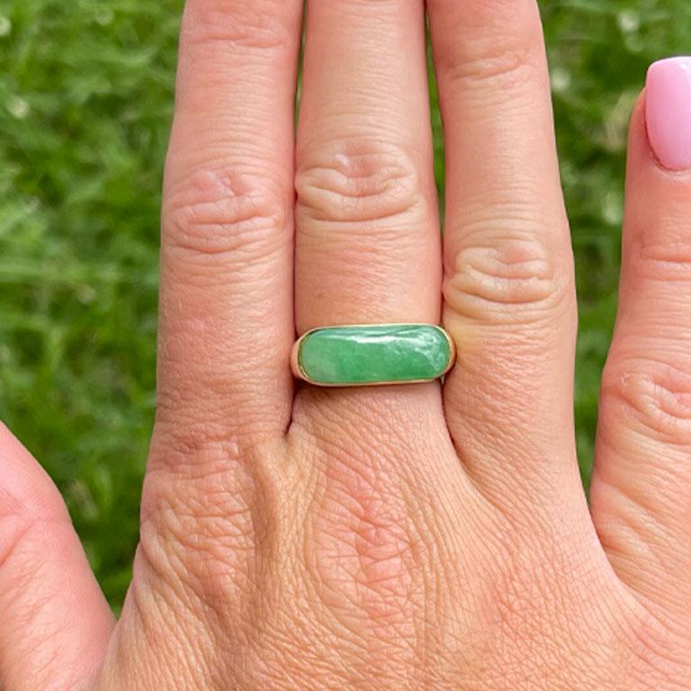 Rectangular shape cabochon green jade ring, bezel set in 14k yellow gold. The Jade measures approximately 20.18 mm x 7.78 mm x 3.47 mm with an estimated weight of 4.91 carats. The ring has a rounded tapered shank with a high polish finish. The ring