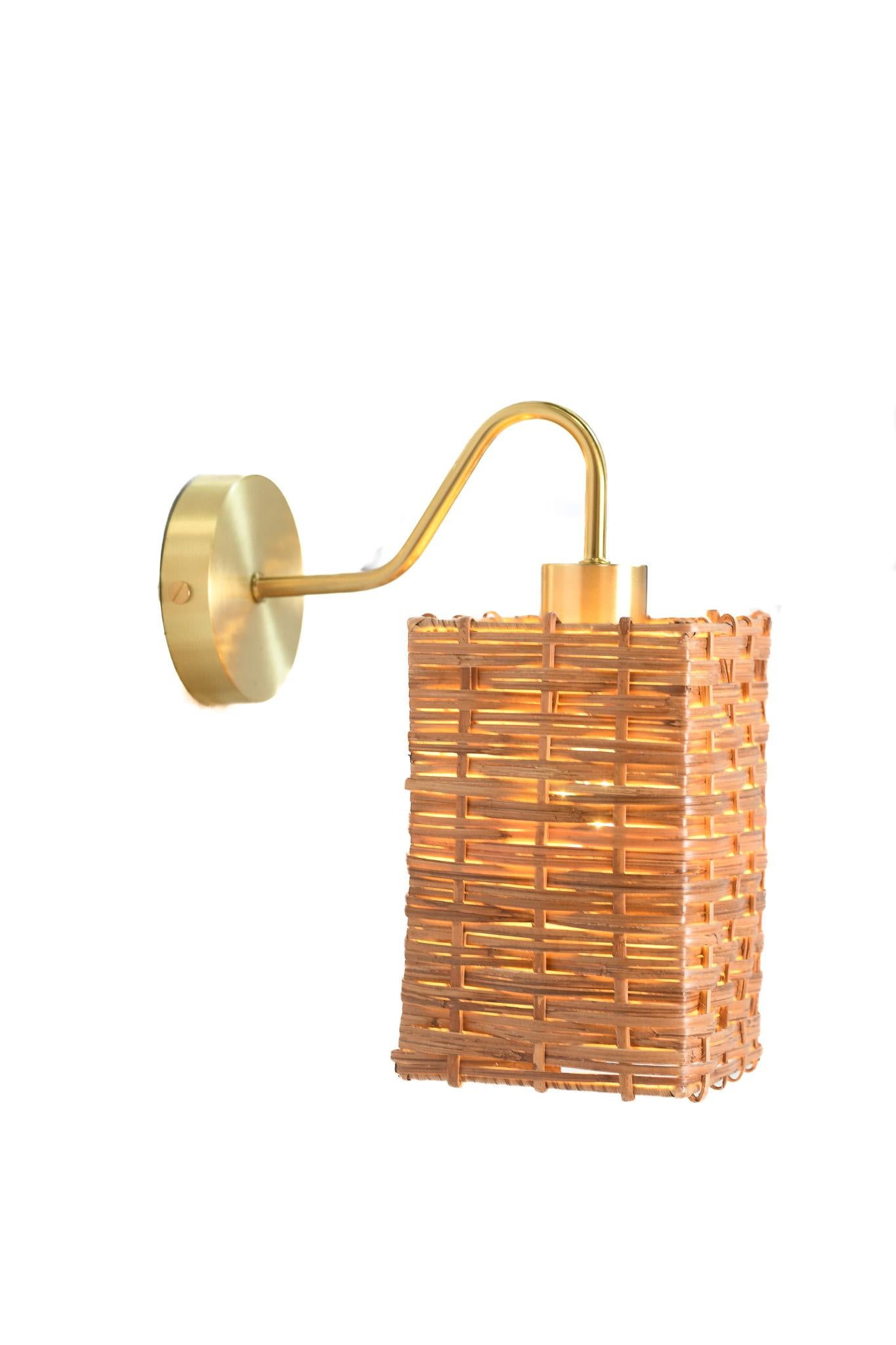 Dieses handgefertigte Beleuchtungsstück zelebriert den natürlichen Charme von Rattan und die Raffinesse von Messing. Diese Leuchte wurde für diejenigen entworfen, die Wert auf handwerkliches Können und warmes Design legen. Sie verleiht jedem