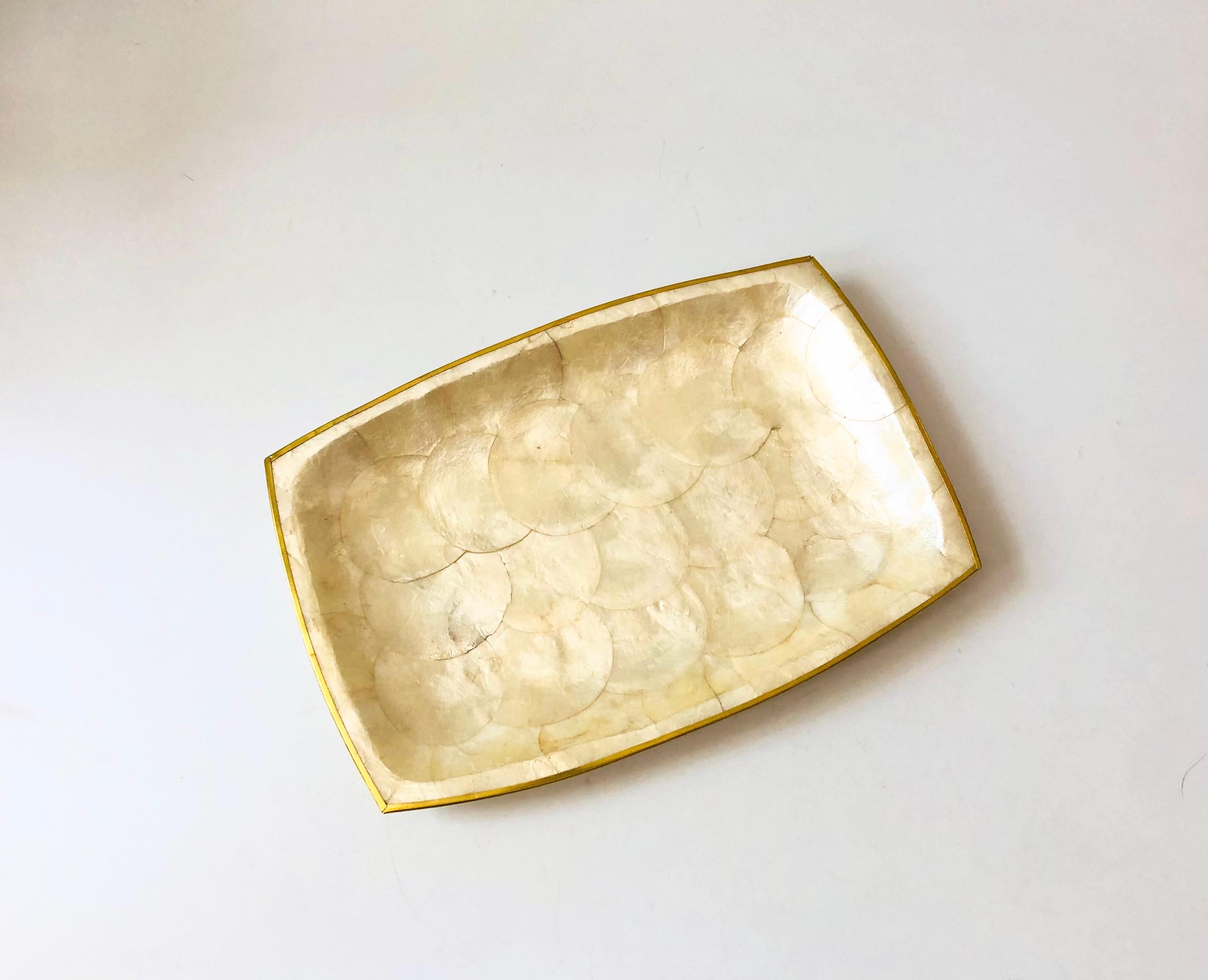 A vintage rectangular capiz shell tray. Edges are trimmed in brass. Lovely variation to the natural semi iridescent capiz shell.

