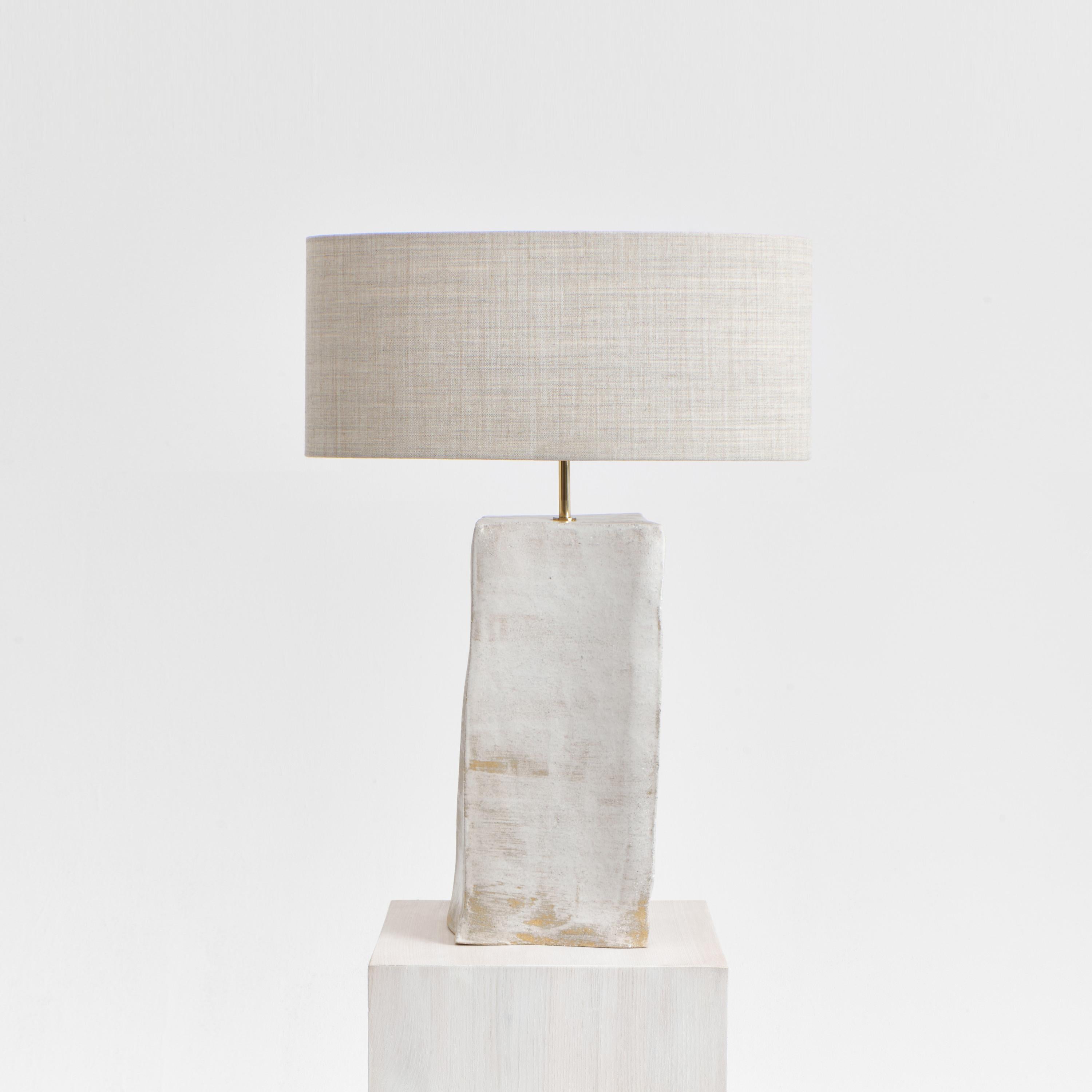 Rectangular Ceramic Light in brushed white
Designed by Project 213A in 2023

Artisanal ceramic light with a rectangular base, made in Project 213A's own ceramic workshop. It has a brass stem and a oval shaped lampshade made from 90%wool, 10% worst
