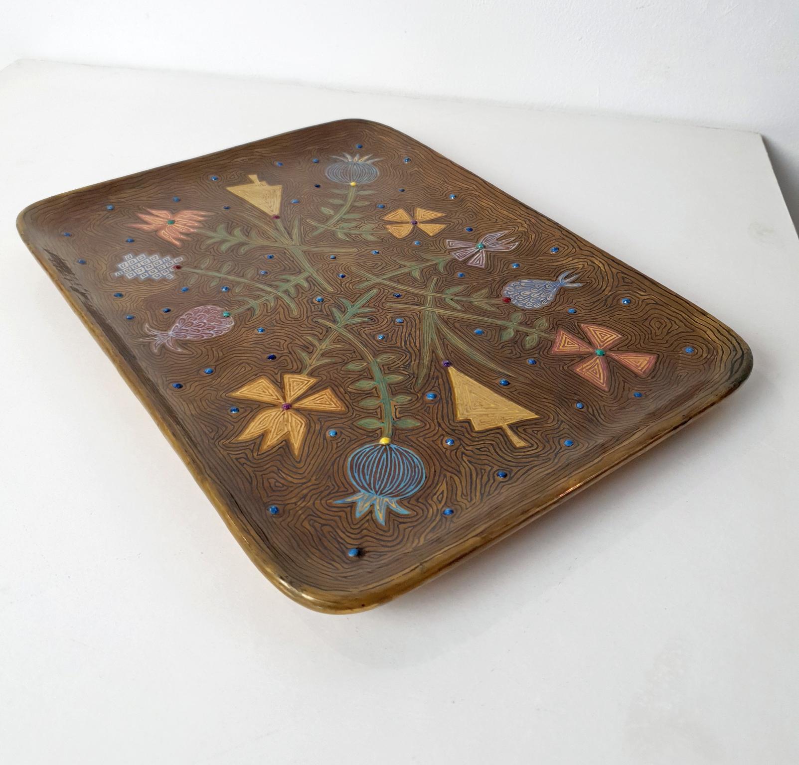 Vassoio realizzato a mano da Studio A Made in Italia. Ha una forma rettangolare con angoli arrotondati e un bordo smussato. La base è di colore oro lushious ed è stata interamente dipinta a mano con frutti e fiori esotici in vari colori. Presenta