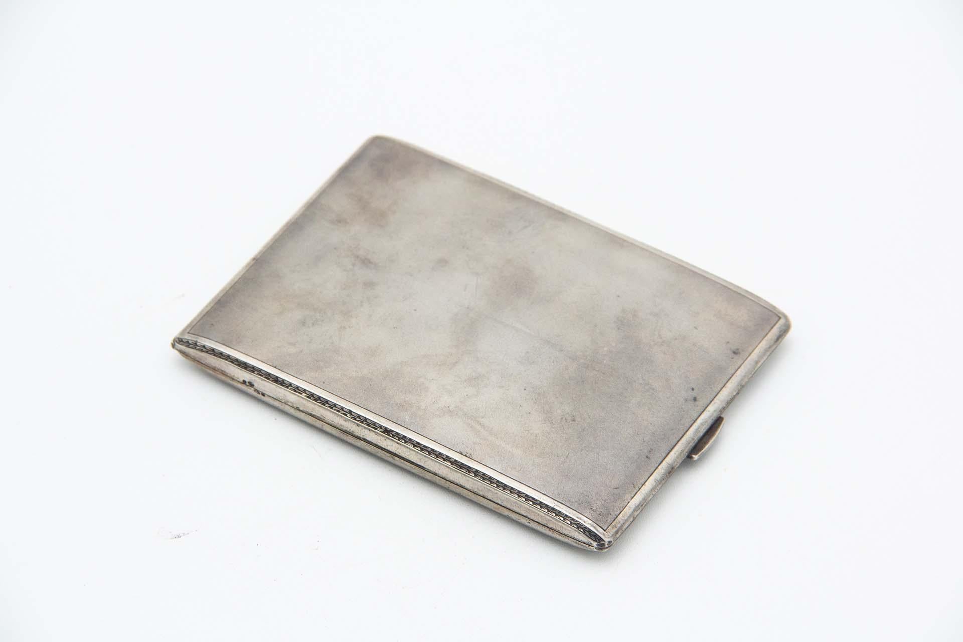 Description: Rectangular cigarette case in matte silver with grooves along the beveled corners and a gold-colored interior. Metal: Silver. Origin: Portuguese. Brand: 833/1000. Weight: 132.66 grams. Dimensions: 11cmx1.2cm. Content: 833/1000. Assay