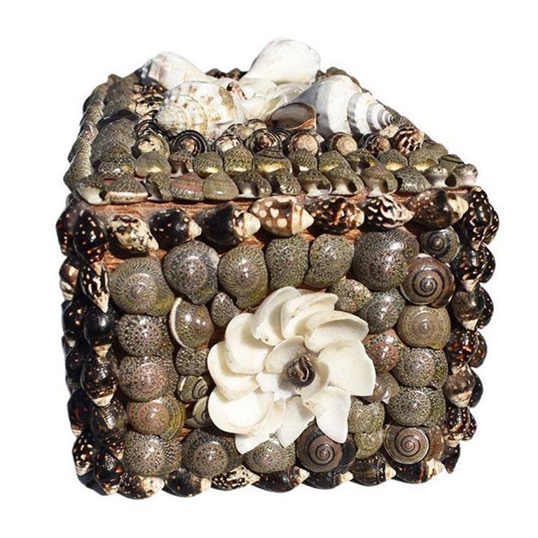 A coastal-style wooden trinket box encrusted with a floral shell motif. A beautiful decorative box that will be great on a nightstand, coffee table, or dressing table. The box is rectangular and created from light wood with a hinged lid at the top.