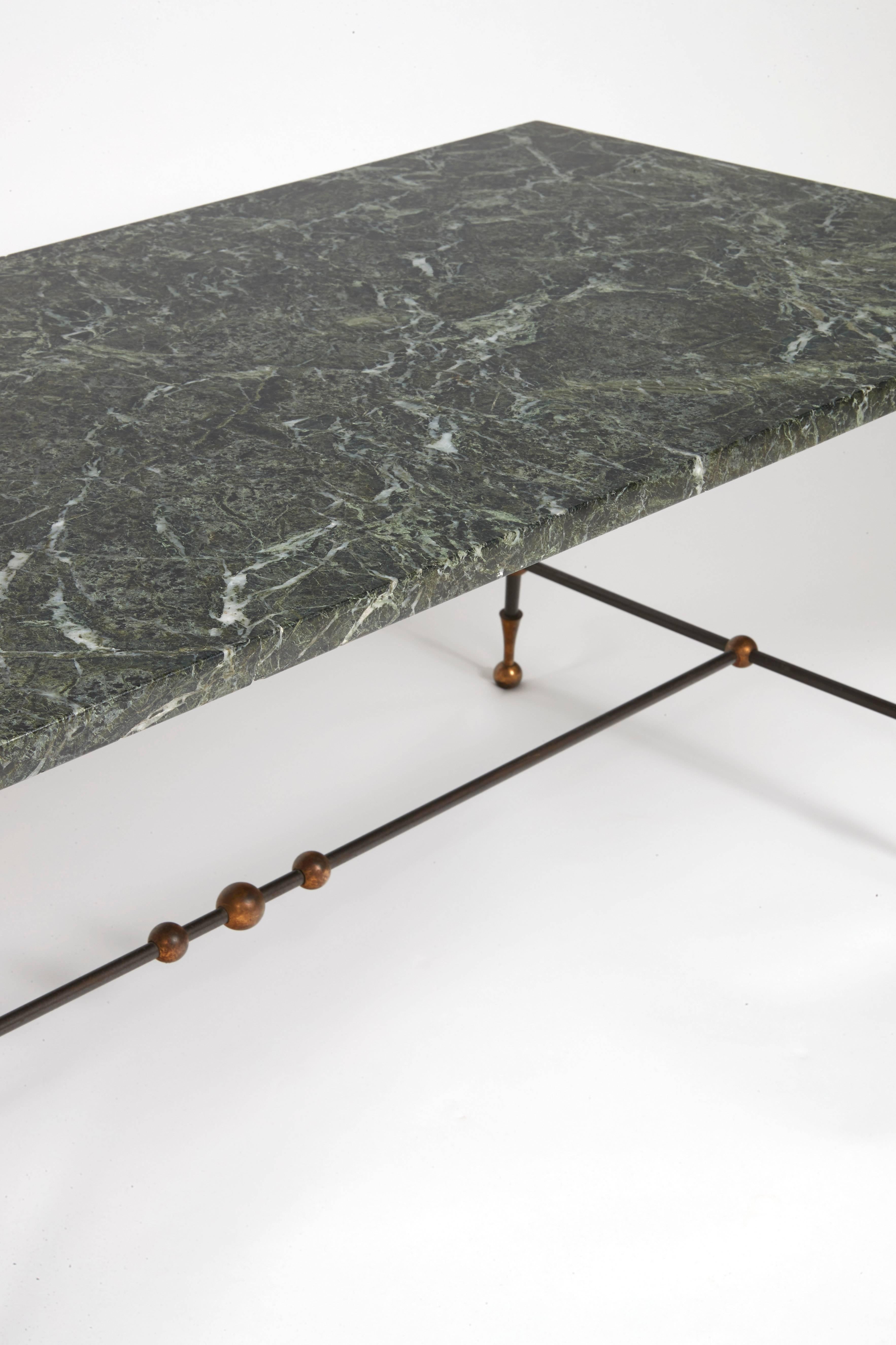 Green and white veined marble top, supported by a black patinated tubular metal base decorated with small balls, gilded metal feet.