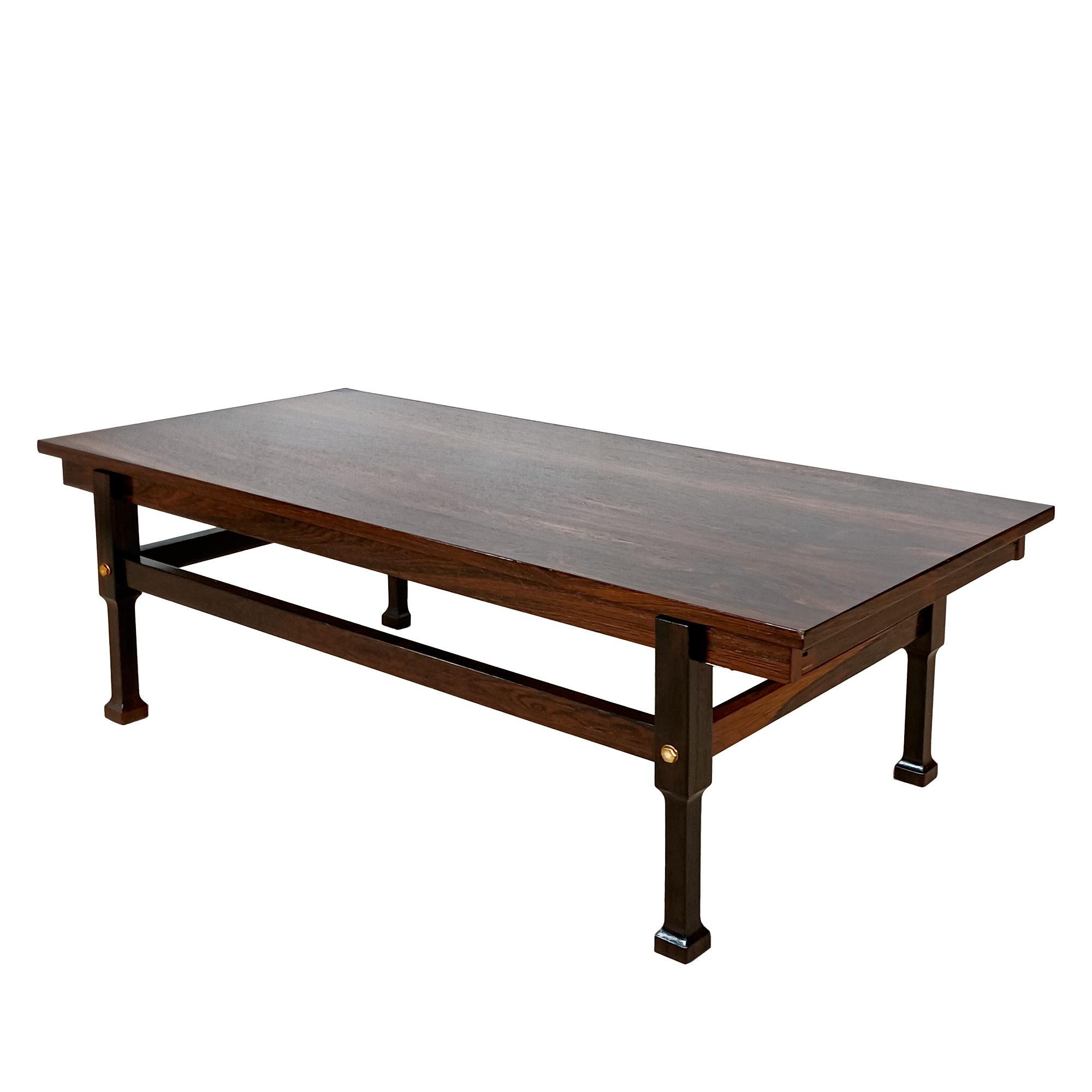 Rechteckiger Couchtisch aus massivem Rio-Palisander und Palisanderfurnier auf vier Beinen, die durch eine Strebe verbunden sind, zwei Schubladen, die als Ablageflächen dienen und an beiden Enden mit rotem Formica überzogen sind, Messingdetails,