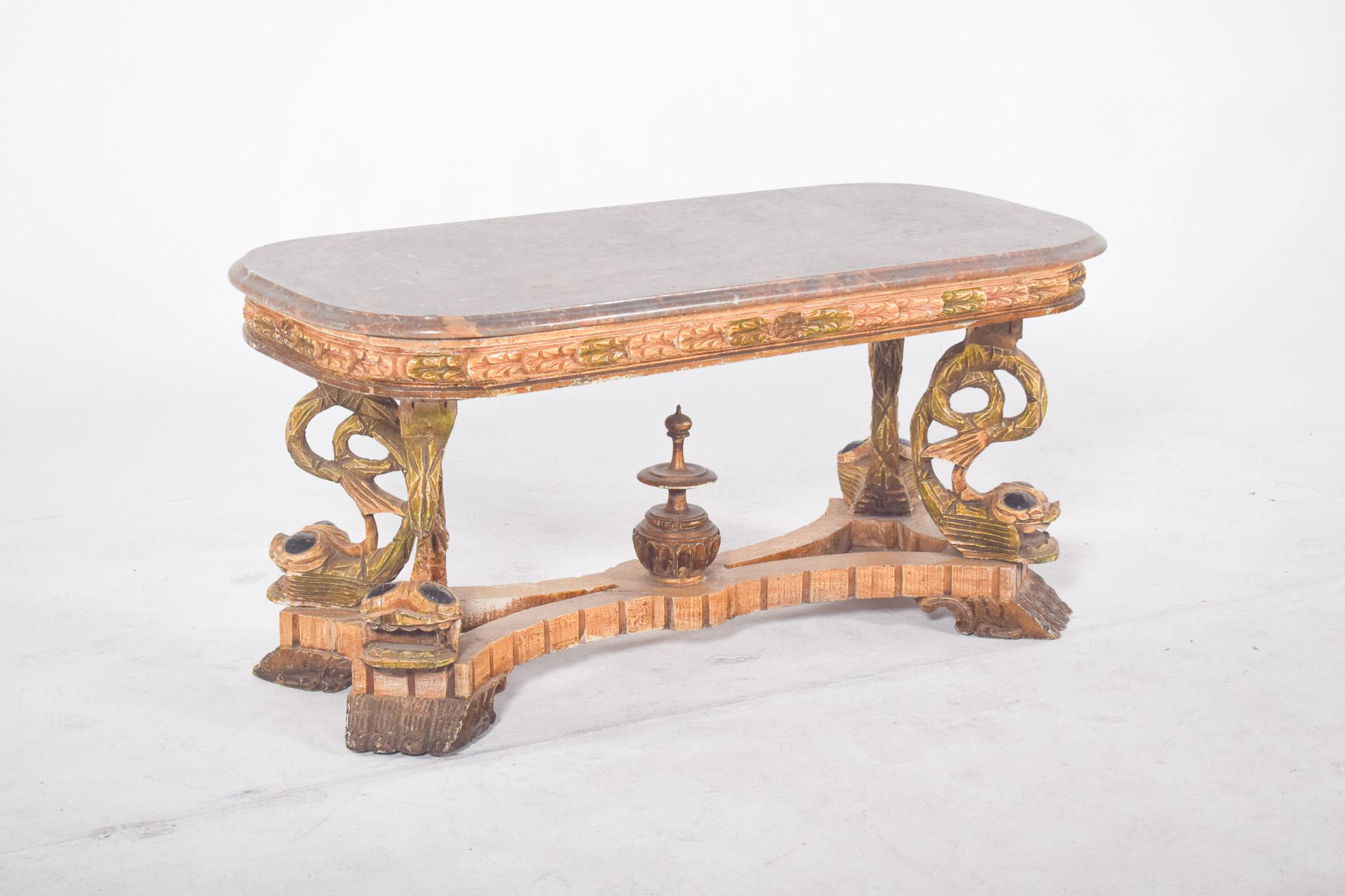 Coffee table with marble top. With a richly carved structure, the highlight of the piece is the sculptural base with decorative elements in high relief, including stylised fish shapes and volutes, painted in gold, green and traces of original